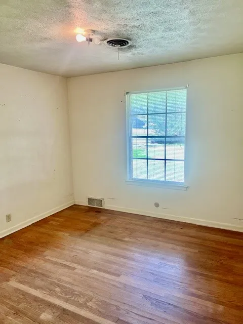 Hardwood flooring and a multi-pane window with horizontal blinds characterize this room