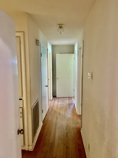 Hallway featuring wood-finish flooring, white walls, and a ceiling-mounted light fixture