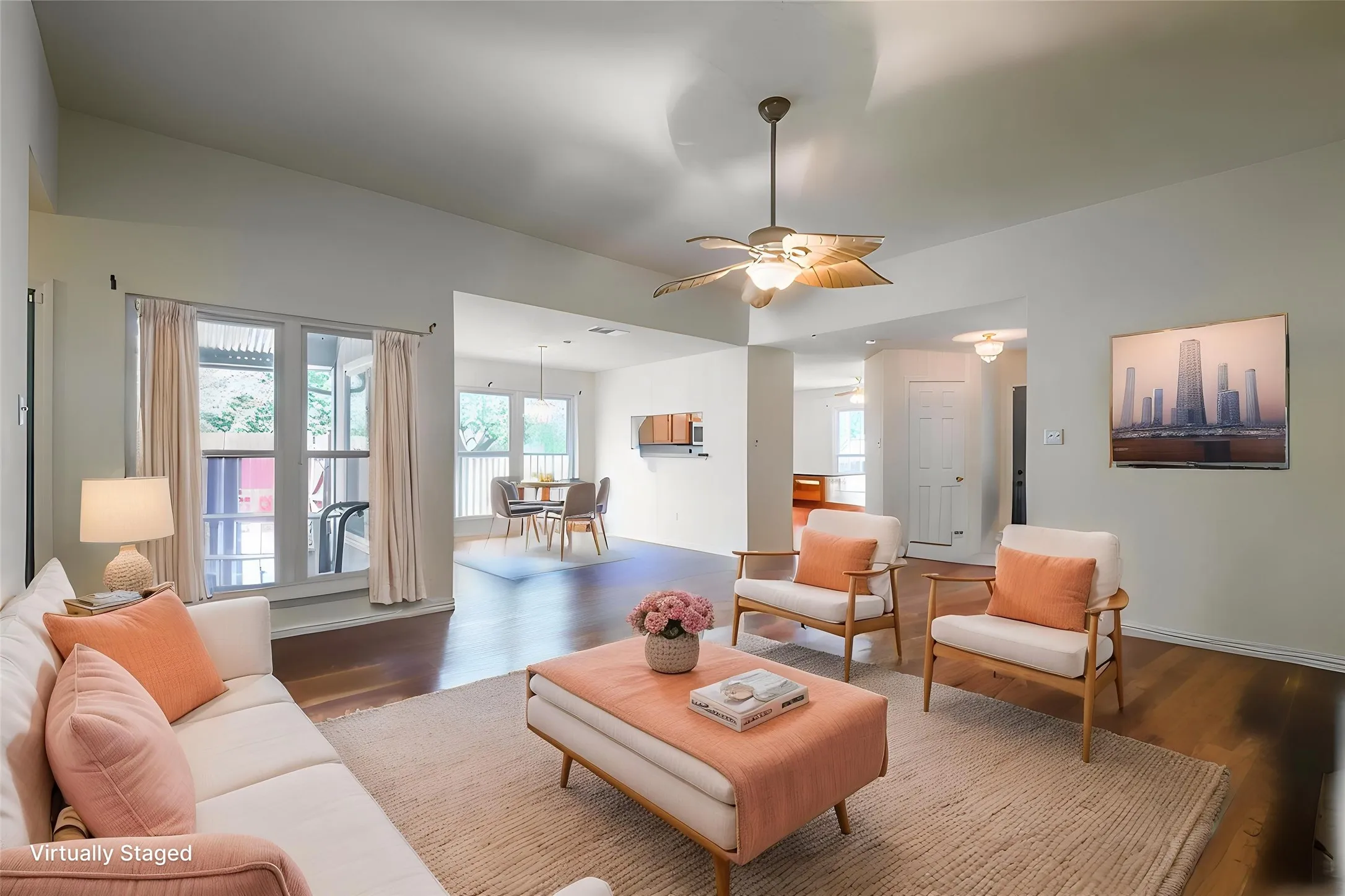 Vaulted ceiling living area featuring wood-finish flooring, a ceiling fan with integrated lighting, and multiple windows