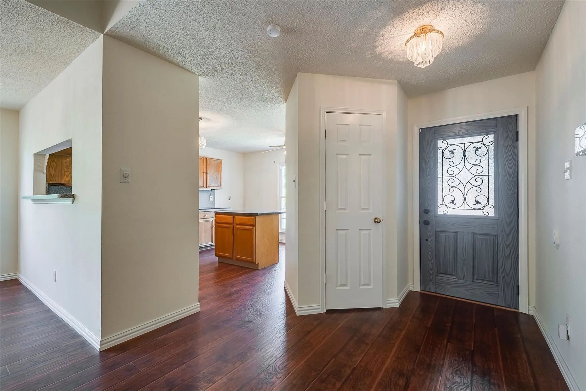 Entryway featuring wood-finish flooring, a decorative glass-paneled front door, a multi-tiered ceiling light fixture, and white trim