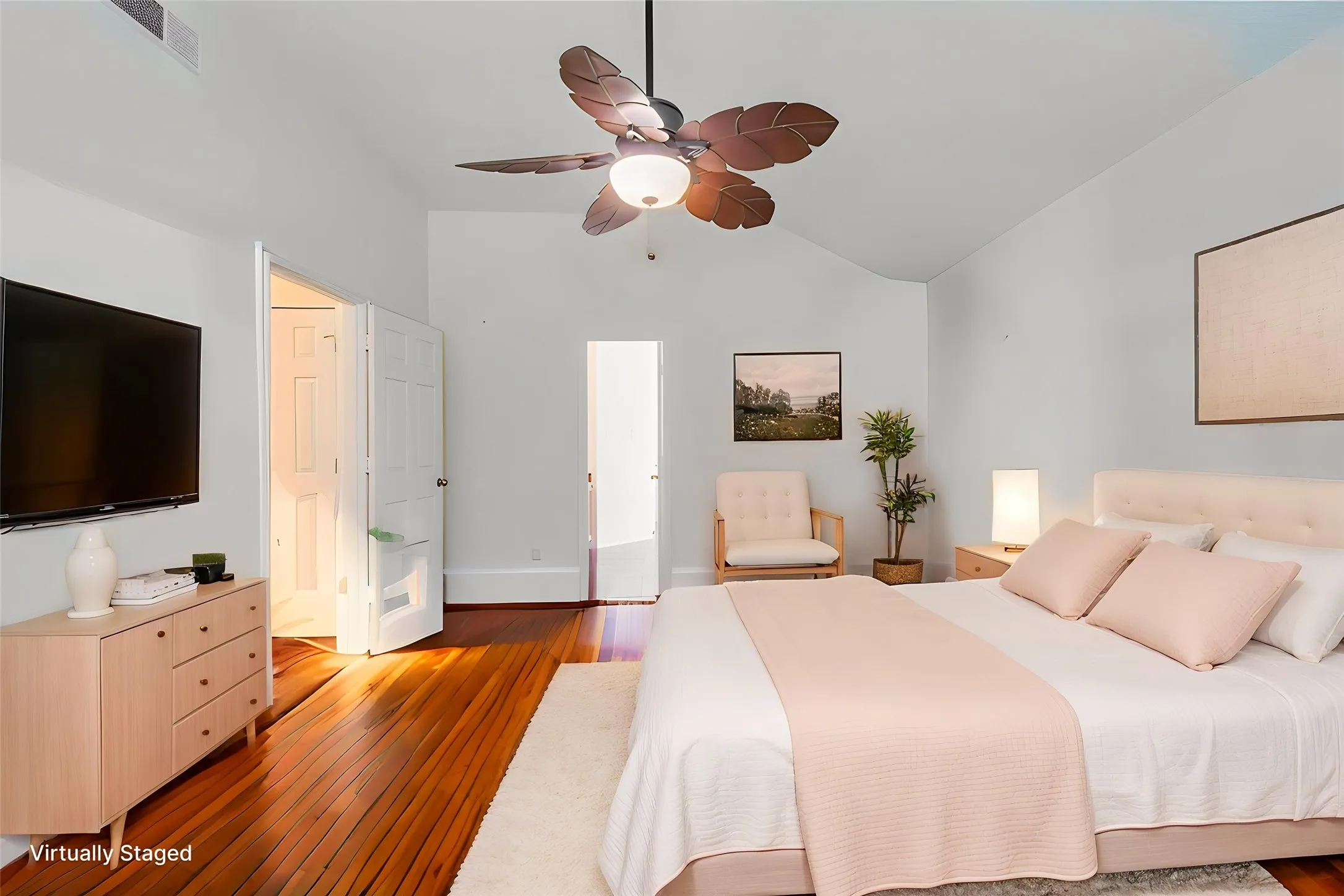 Vaulted ceiling bedroom featuring wood-finish flooring, a ceiling fan with integrated lighting, and multiple doorways