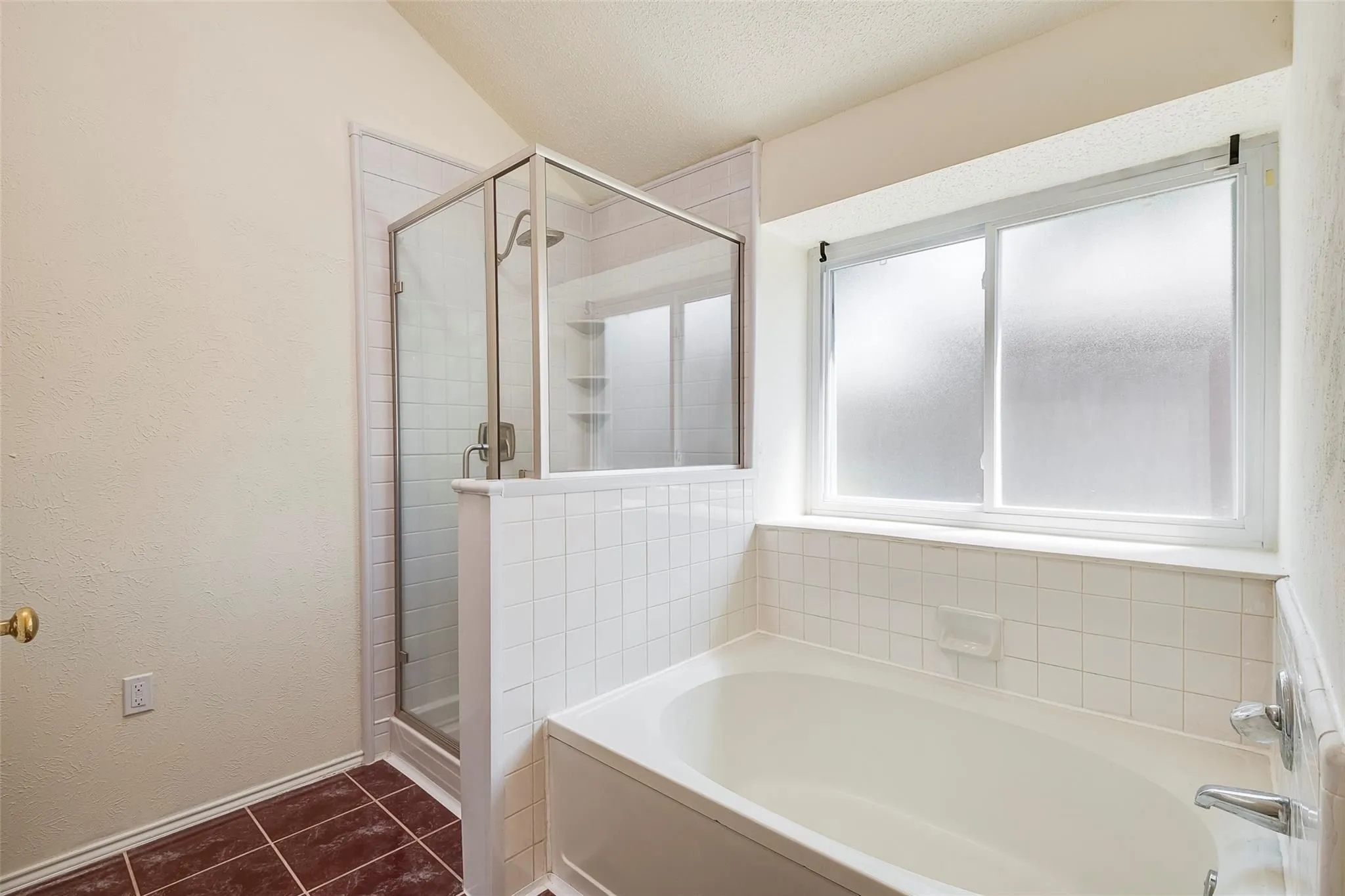 Bathroom featuring a full-size bathtub, white tile surround, and a frosted window