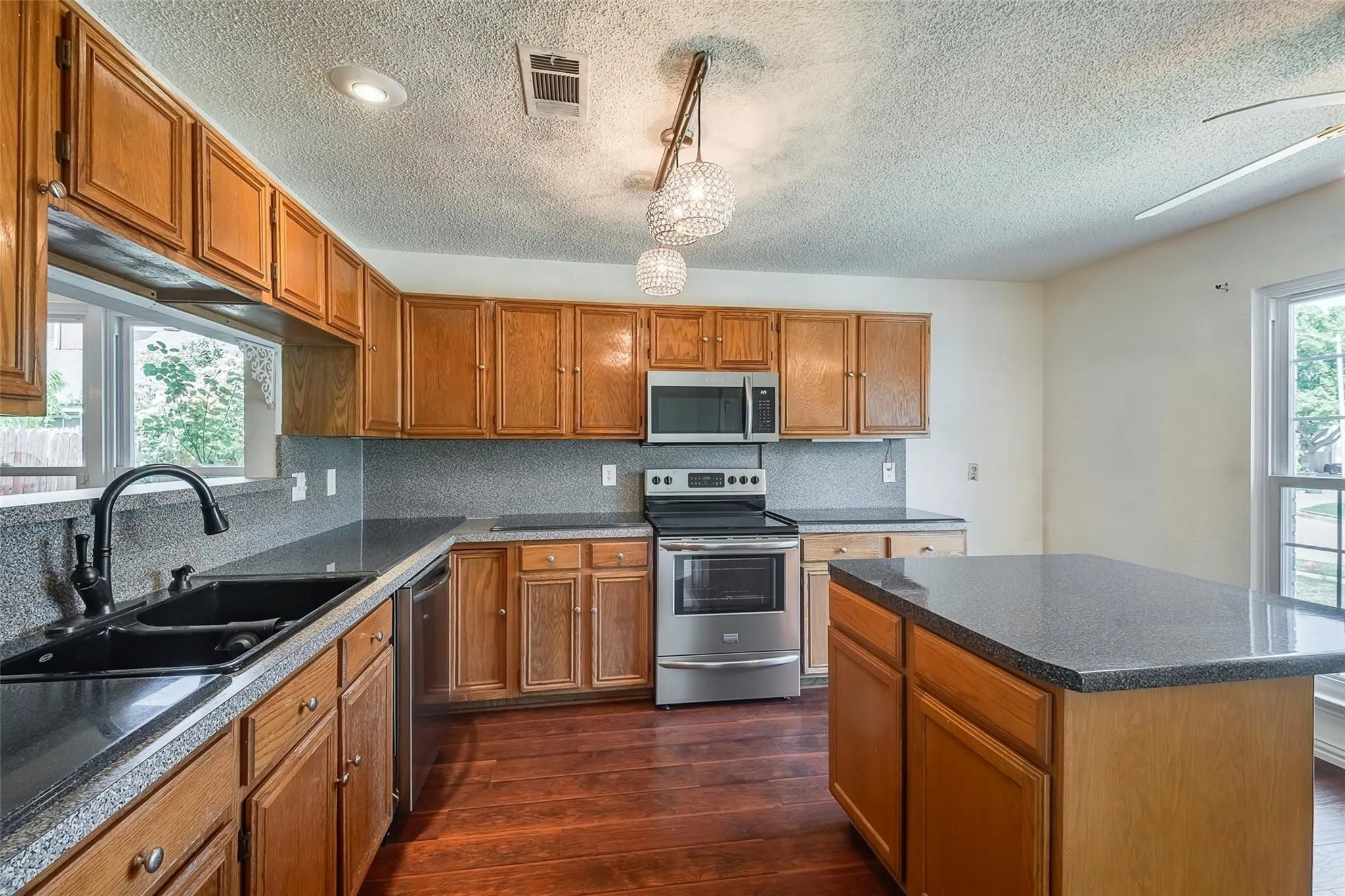 Kitchen featuring wood-finish cabinetry, dark countertops, and stainless steel appliances