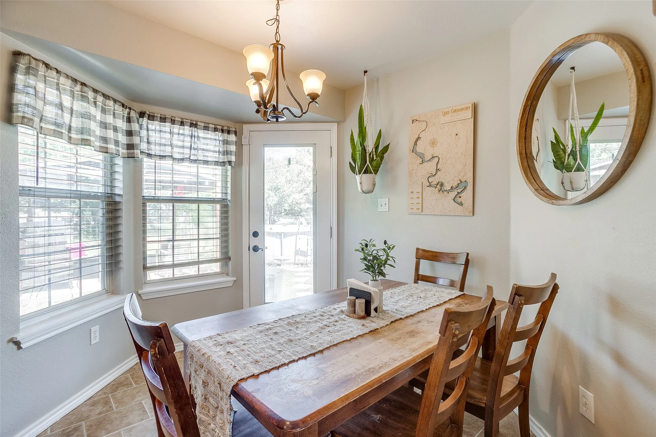 Dining area featuring an angled bay window with blinds, a glass-panel door, and tiled flooring