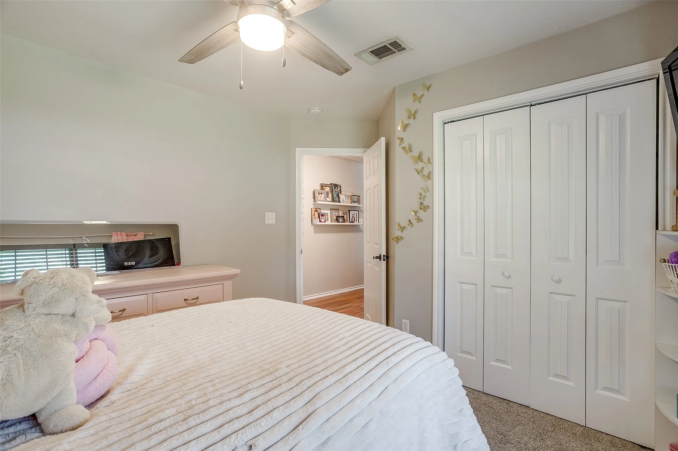 Bedroom featuring light neutral wall tones, bi-fold closet doors, a ceiling fan with light fixture, and carpet flooring