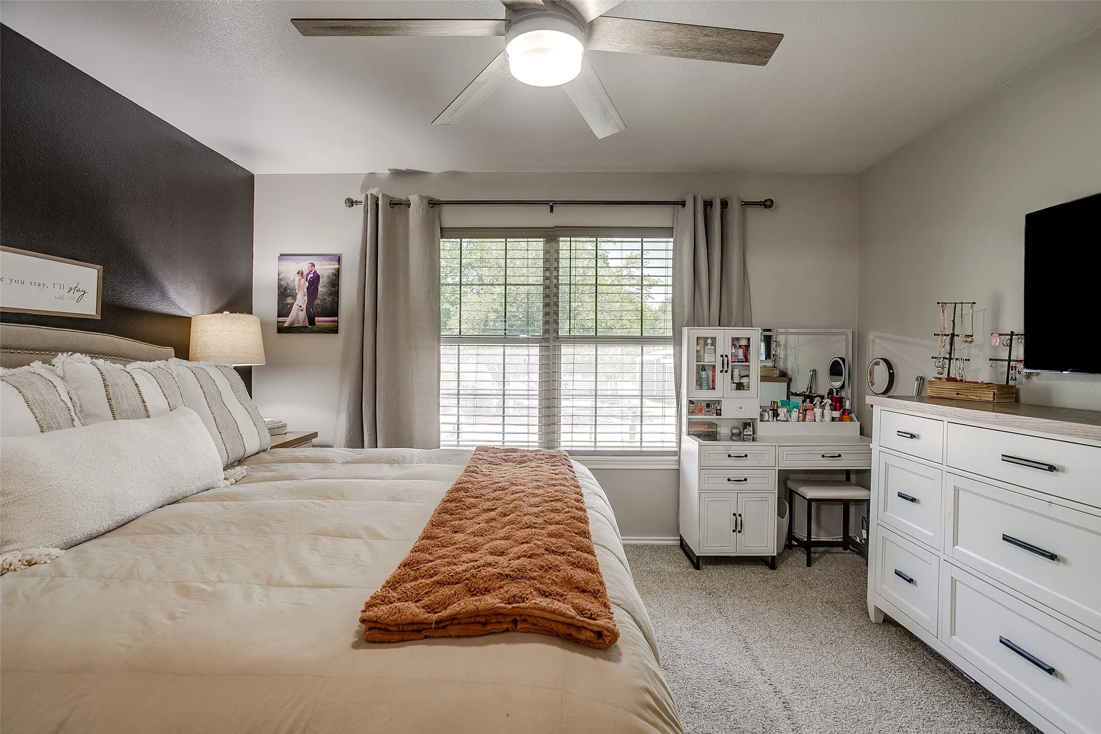 Bedroom featuring a ceiling fan, carpet flooring, and a large window with horizontal blinds