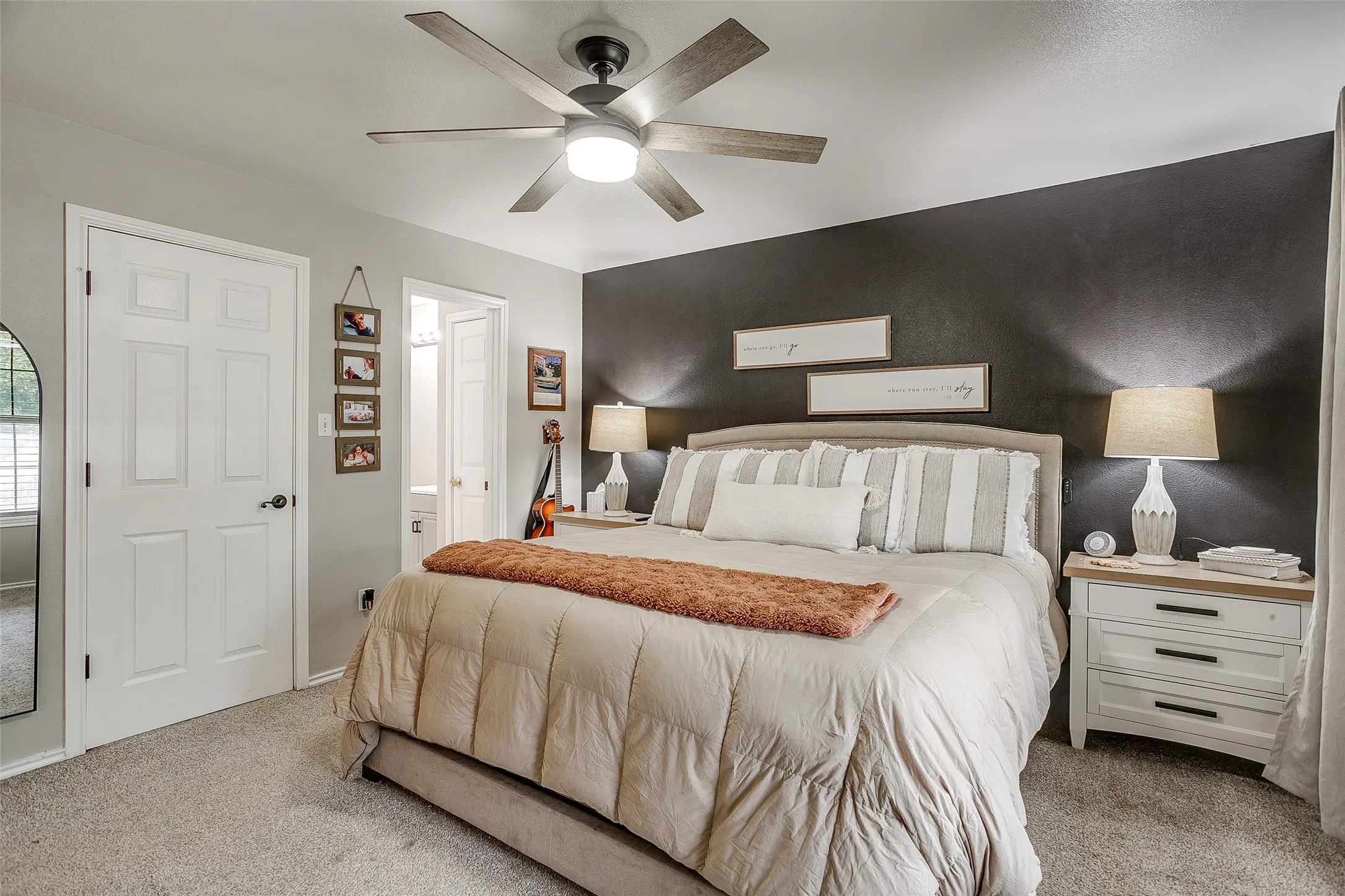 Bedroom featuring a dark accent wall, ceiling fan with integrated lighting, and carpet flooring