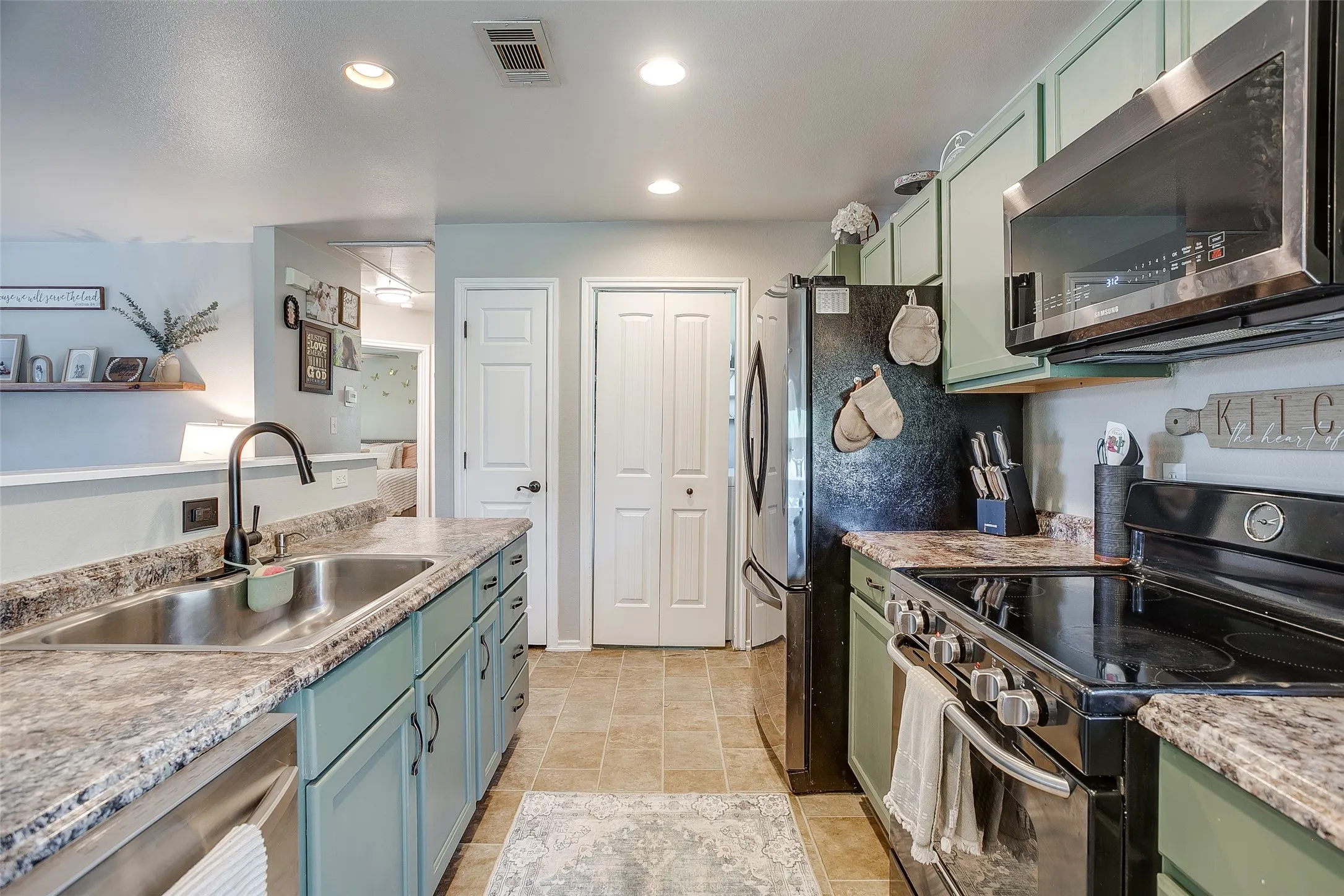 Efficient kitchen featuring a stainless steel double basin sink with a matte black faucet, granite-look countertops, and recessed lighting