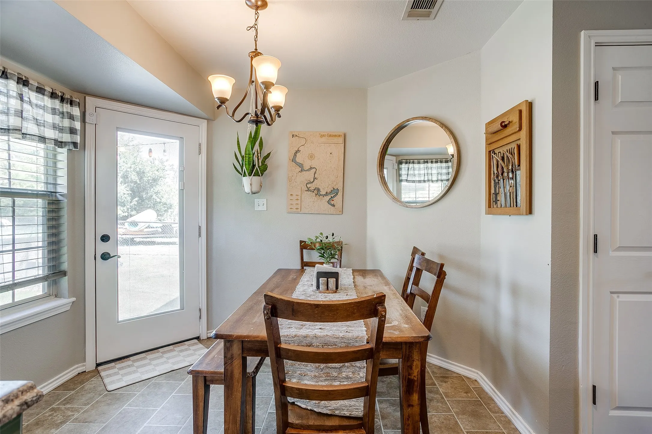 Dining area featuring neutral wall tones, tile flooring, a full-lite exterior door, and an overhead chandelier