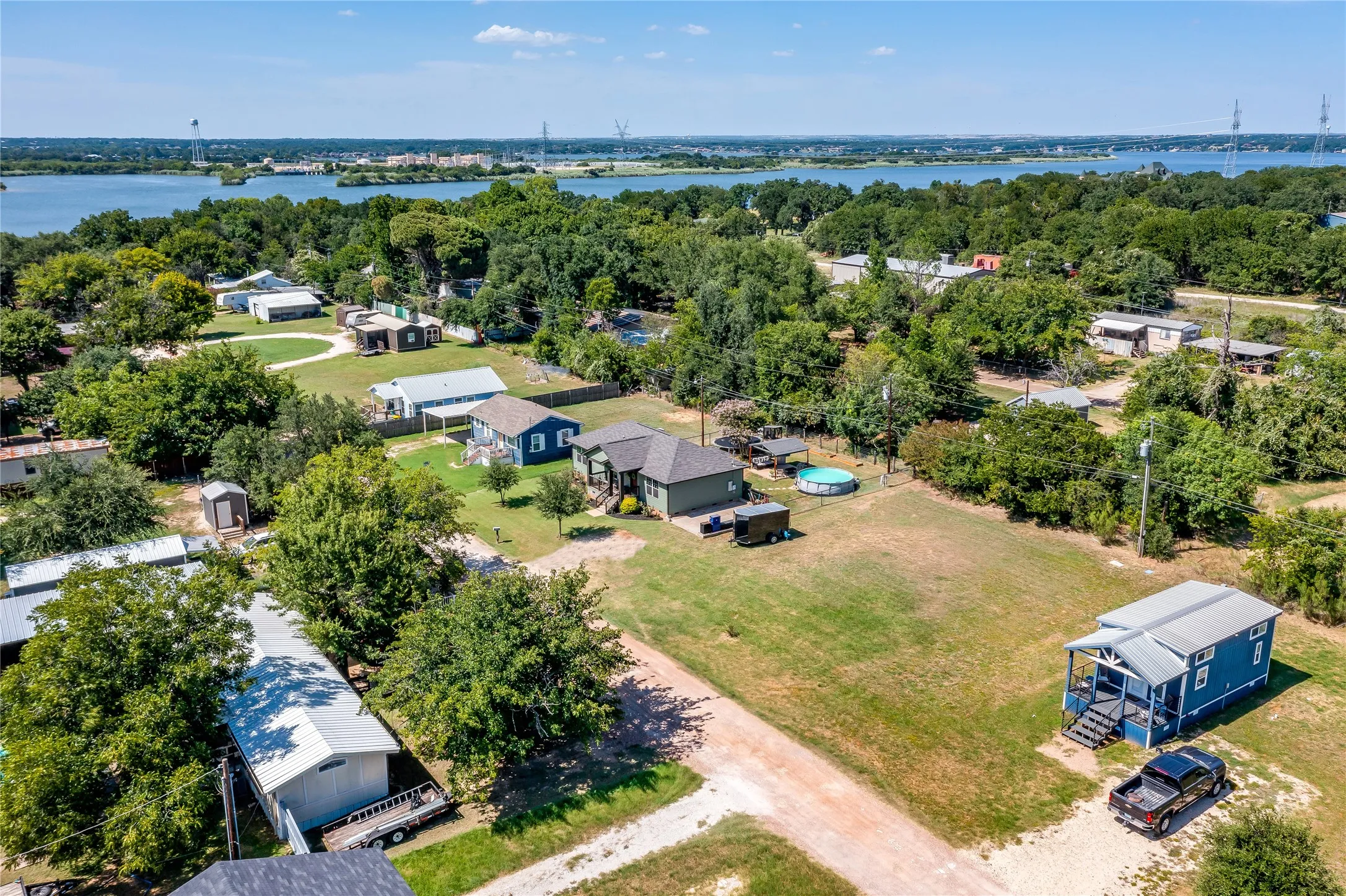Expansive residential area featuring a prominent water body, mature trees, and varied property types