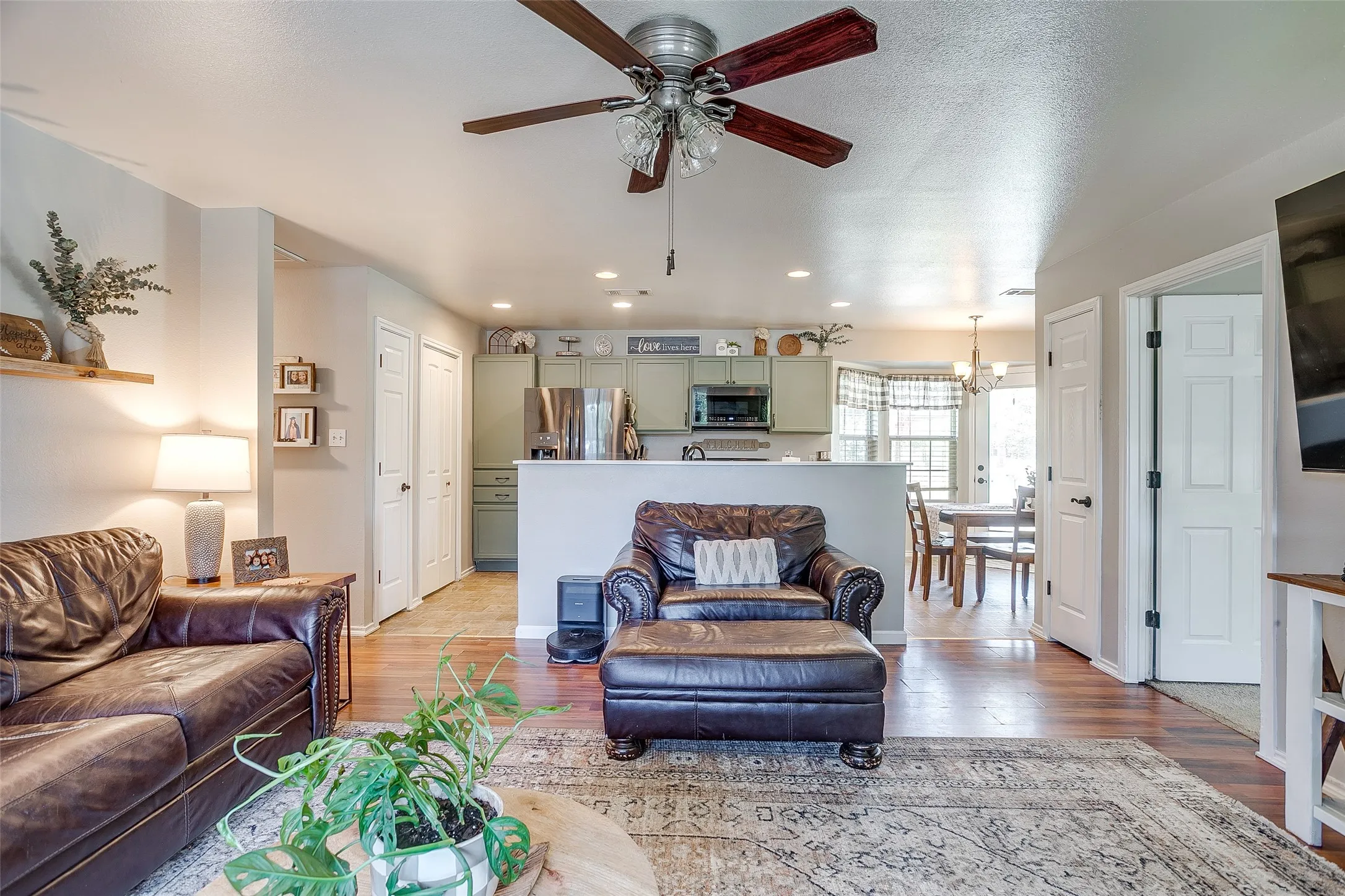 Open-concept living space featuring wood-finish flooring, a ceiling fan, light gray wall tones, and recessed lighting