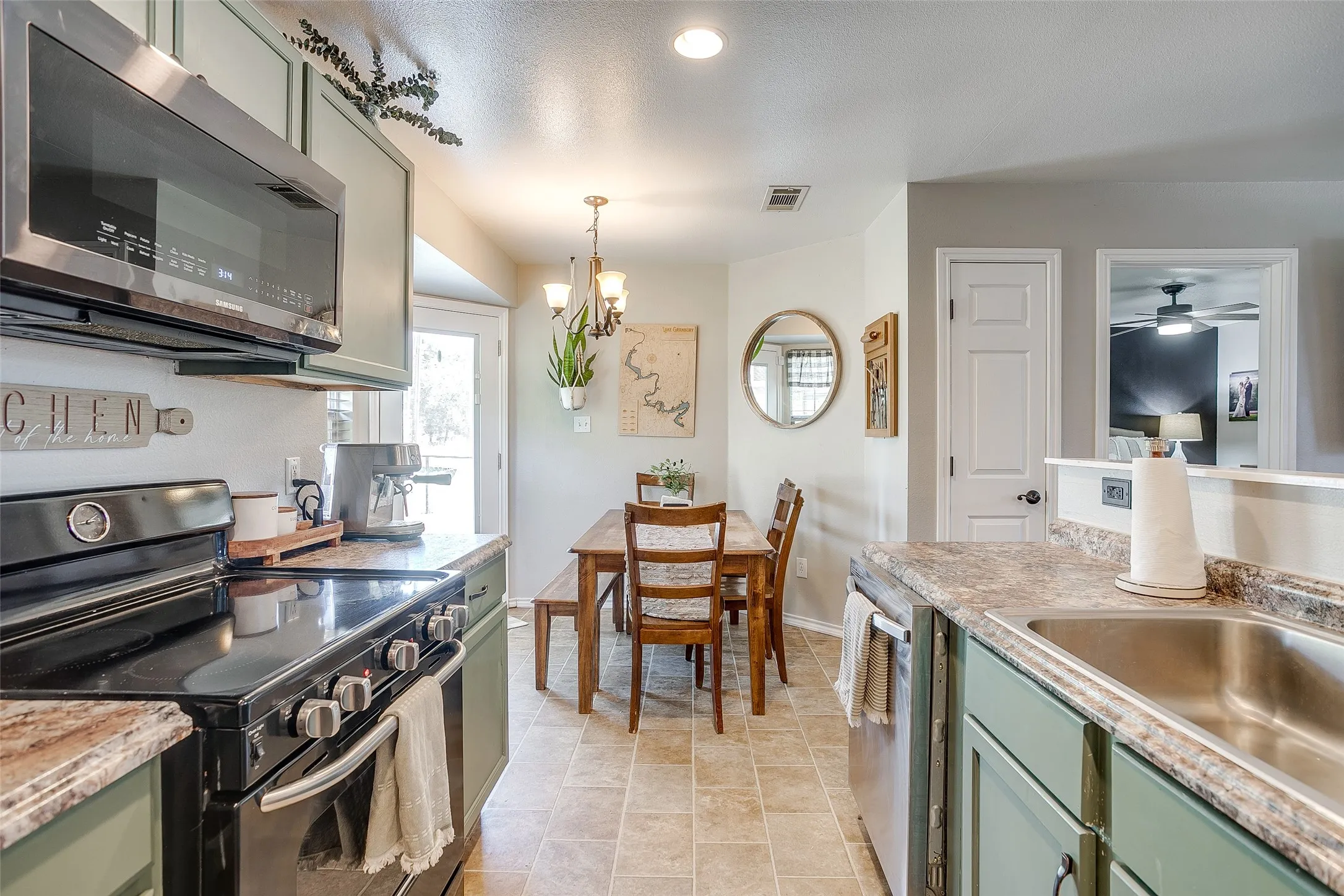 Kitchen and dining area featuring sage green cabinetry, a built-in stainless steel microwave, black electric range, and light-toned countertop