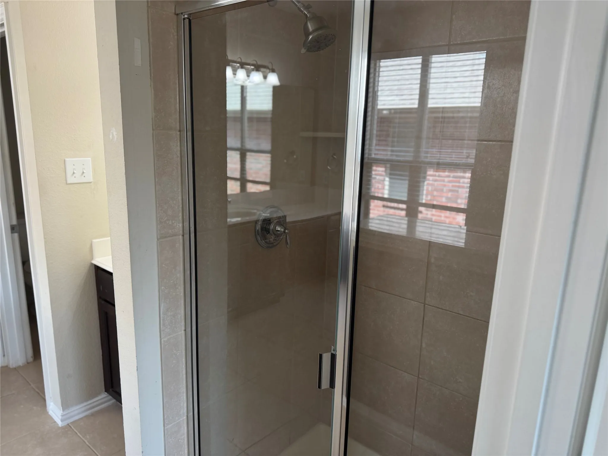 Enclosed shower with clear glass door, large format tile surround, and chrome shower fixtures