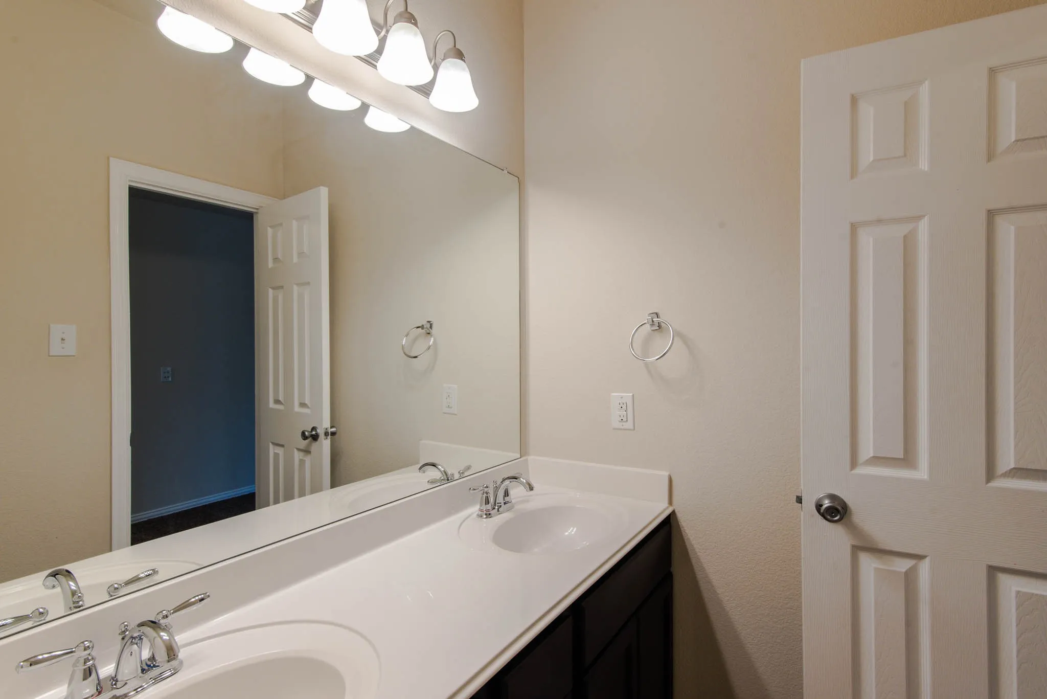 Dual vanity featuring white undermount sinks, chrome faucets, and a full-width mirror