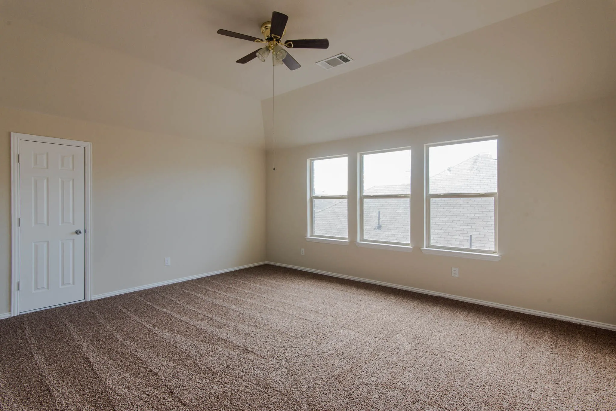 Expansive room featuring textured carpeting, three transom windows, a multi-paneled door, and a ceiling fan with integrated lighting