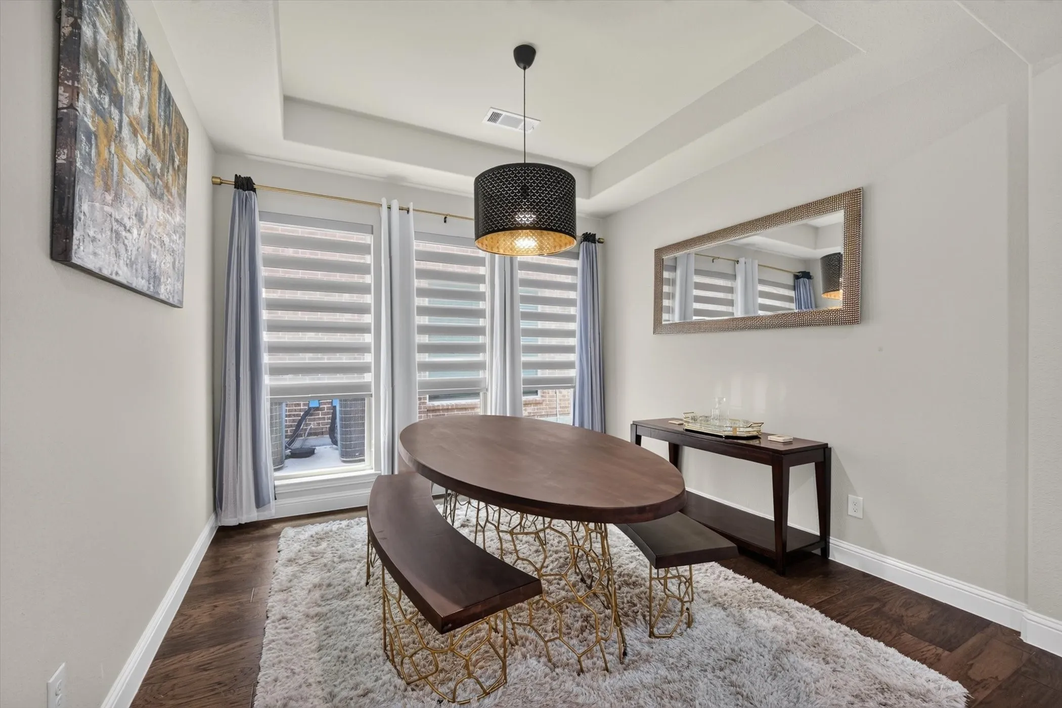 Recessed lighting and a modern pendant fixture illuminate this room featuring wood-finish flooring