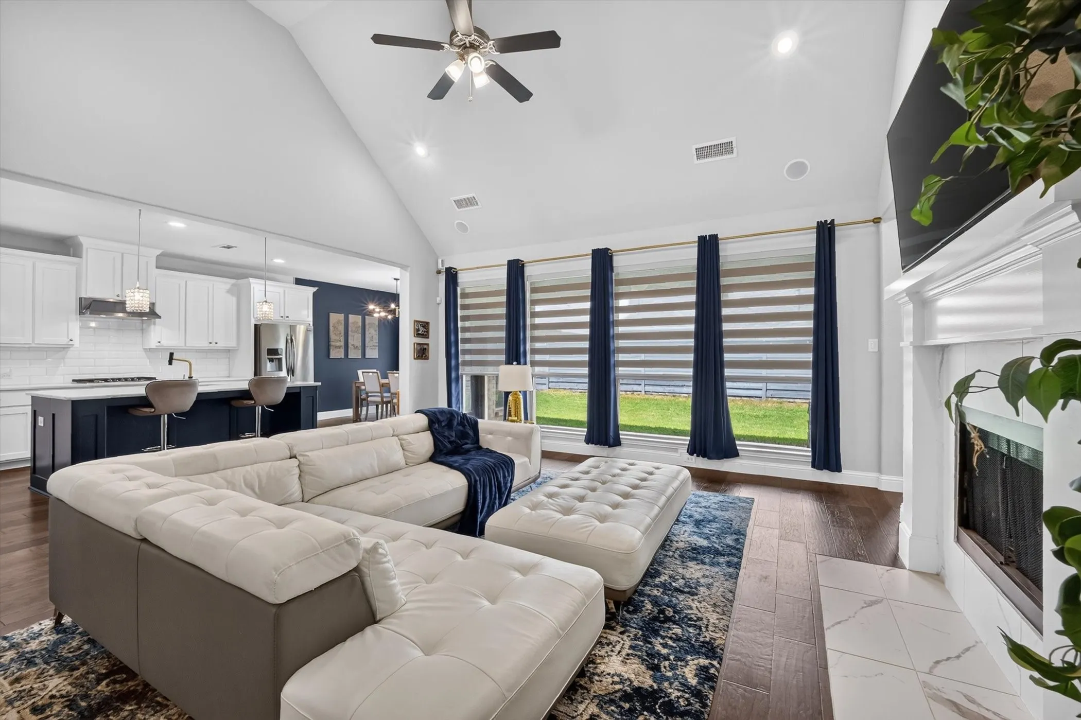 Vaulted ceiling living area featuring wood-finish flooring and a white mantel fireplace
