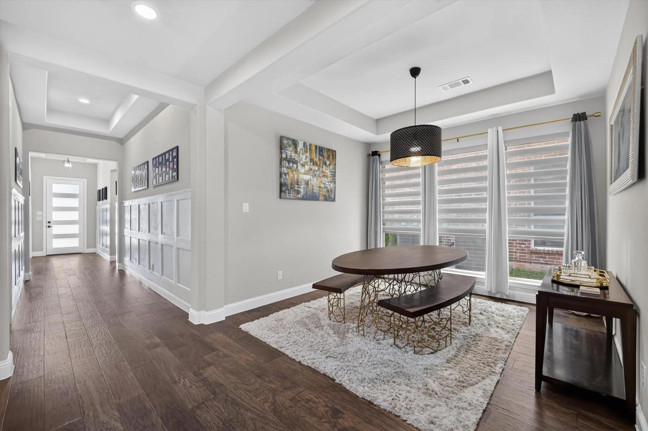 Dining area featuring three large windows with roller shades, a contemporary pendant light fixture, and a tray ceiling
