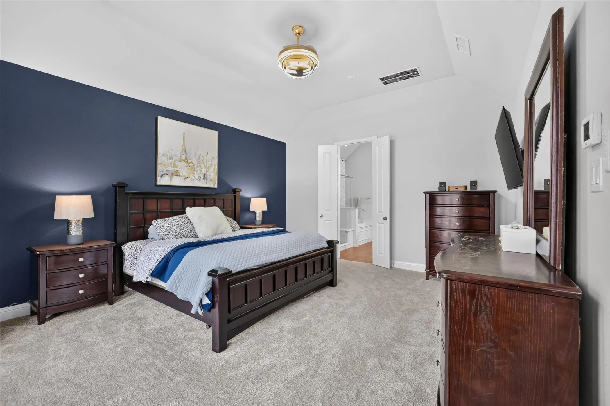 Carpeted bedroom with a vaulted ceiling and a prominent accent wall