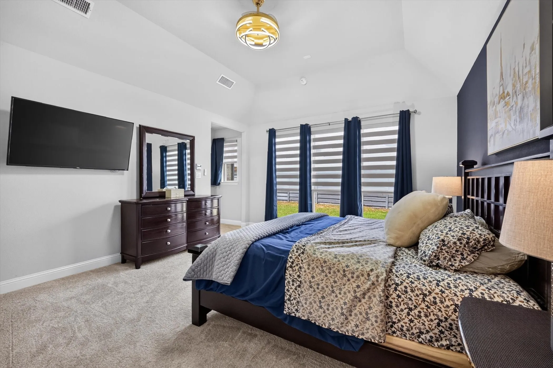 Vaulted ceiling bedroom featuring carpeting, a dark accent wall, and multiple windows with blinds and curtains