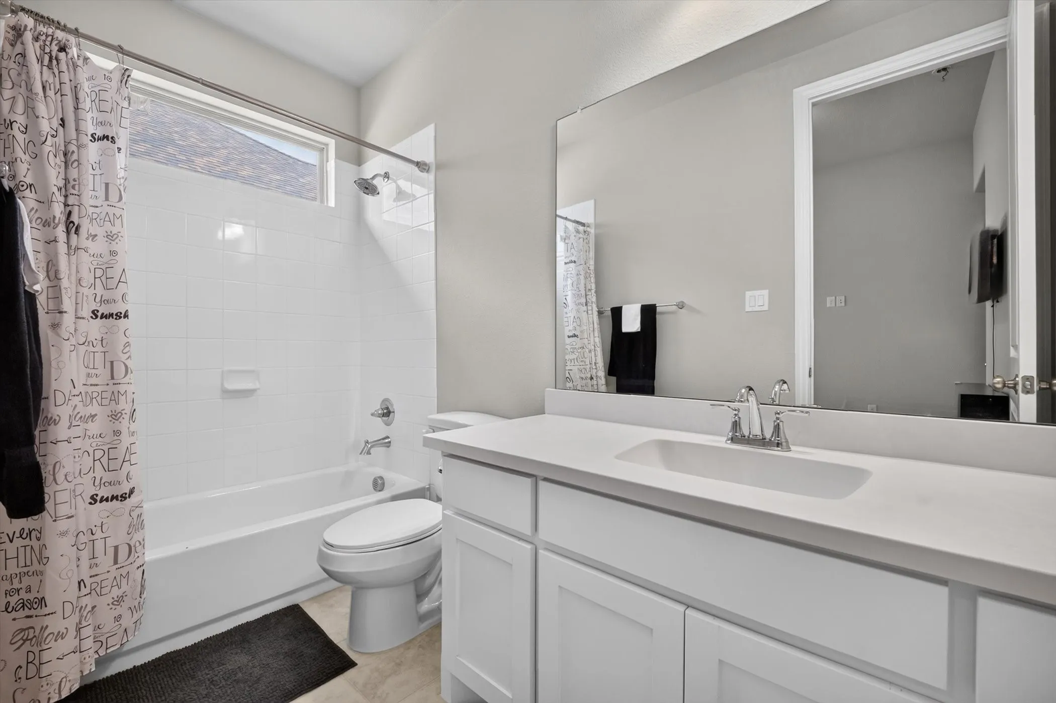 Bathroom featuring a white vanity with integrated sink, chrome faucet, and a large wall-mounted mirror