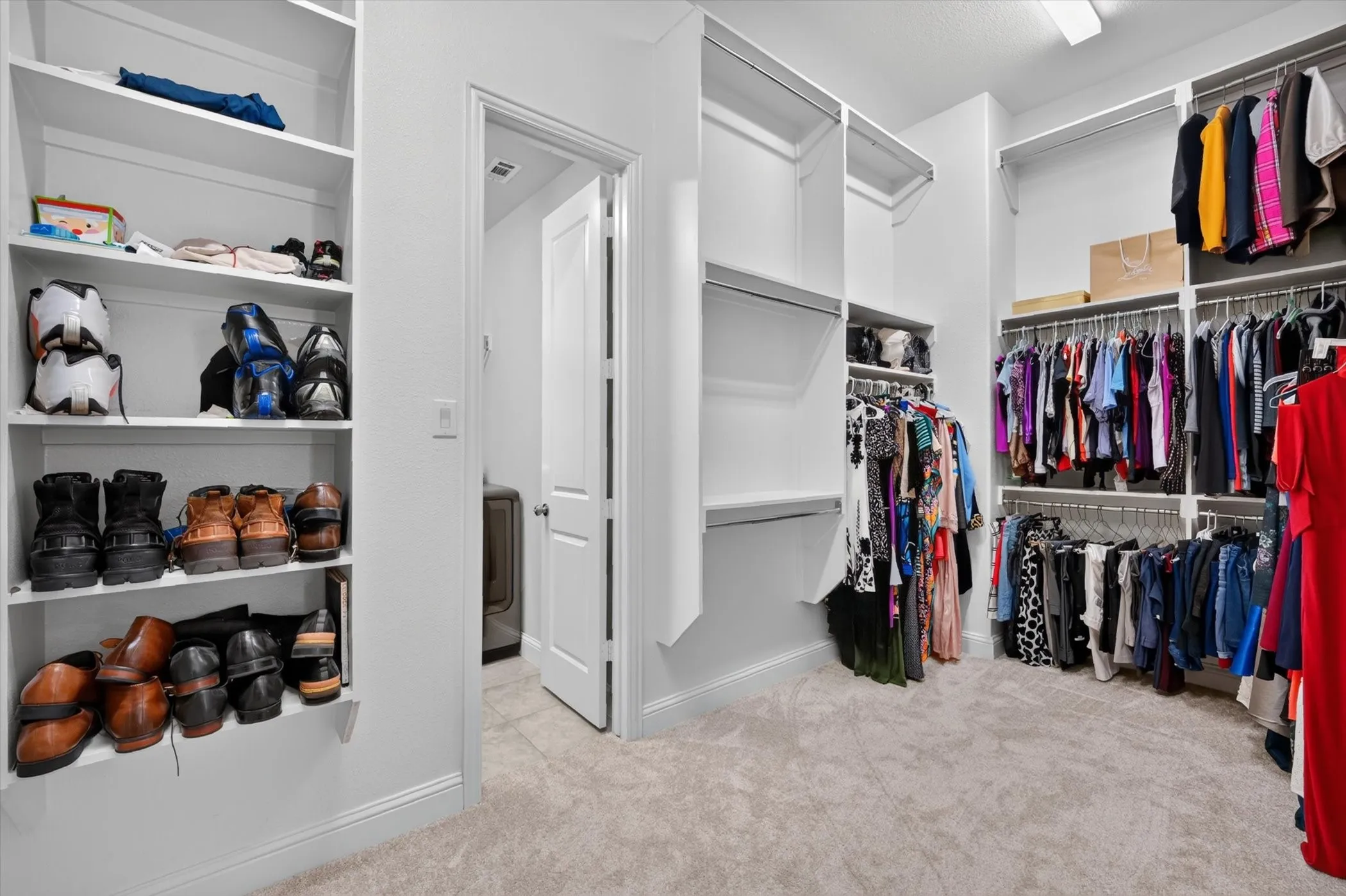 Expansive walk-in closet featuring built-in shelving, multiple hanging rods, and light-toned carpeting