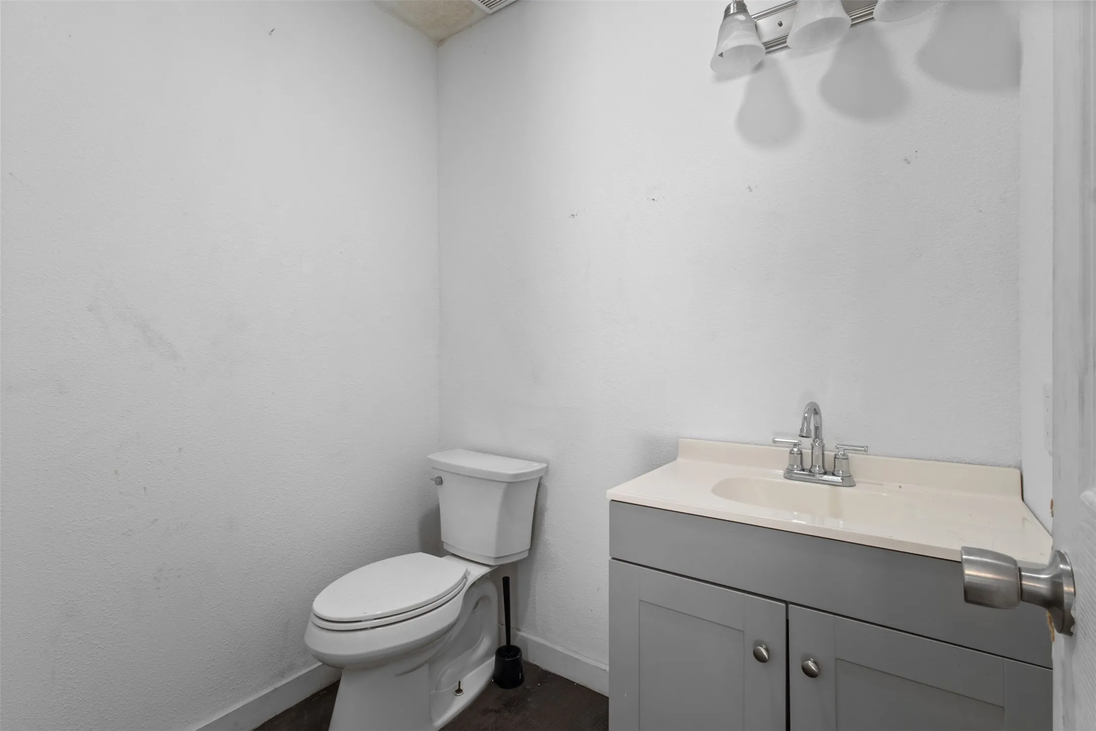 Powder room featuring a single vanity with a light gray cabinet, a white countertop, and a chrome faucet
