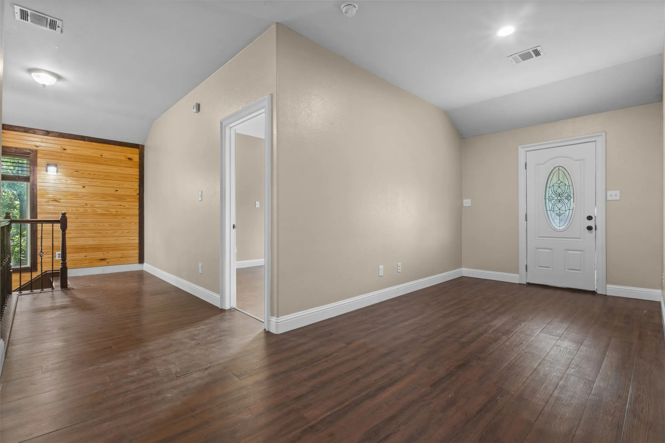 Entry area featuring rich wood-finish flooring, light neutral wall tones, and white trim
