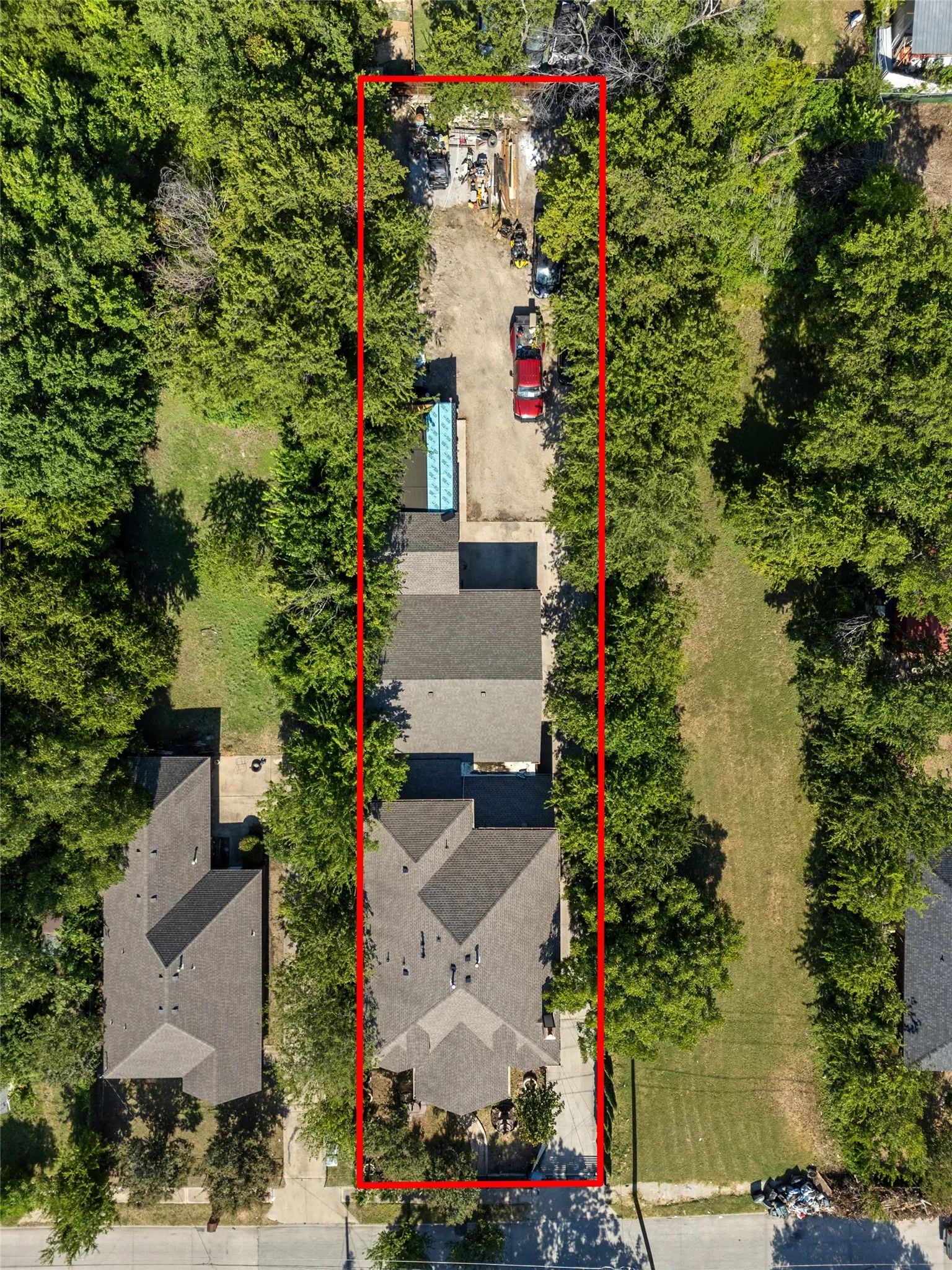 Expansive property featuring a multi-gabled main residence, an additional structure with a light blue roof, and a gravel driveway extending to the rear