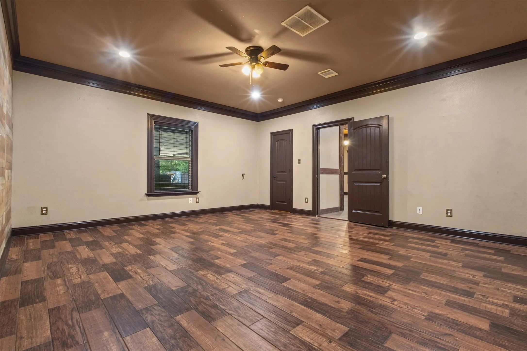 Spacious room featuring wood-finish flooring, dark trim accents, recessed lighting, and a ceiling fan