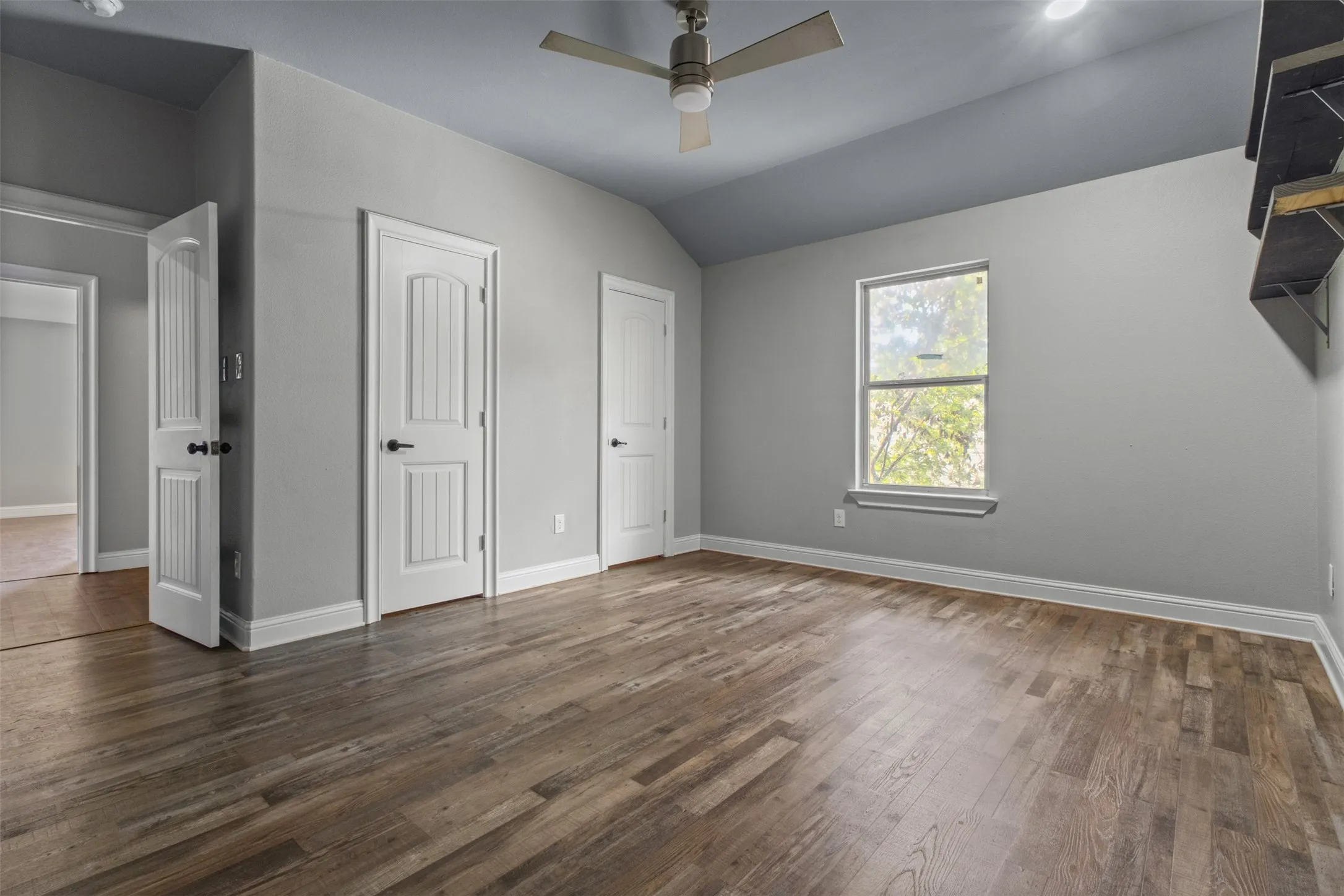 Spacious room featuring wood-finish flooring, a contemporary ceiling fan, and ample natural light from a large window