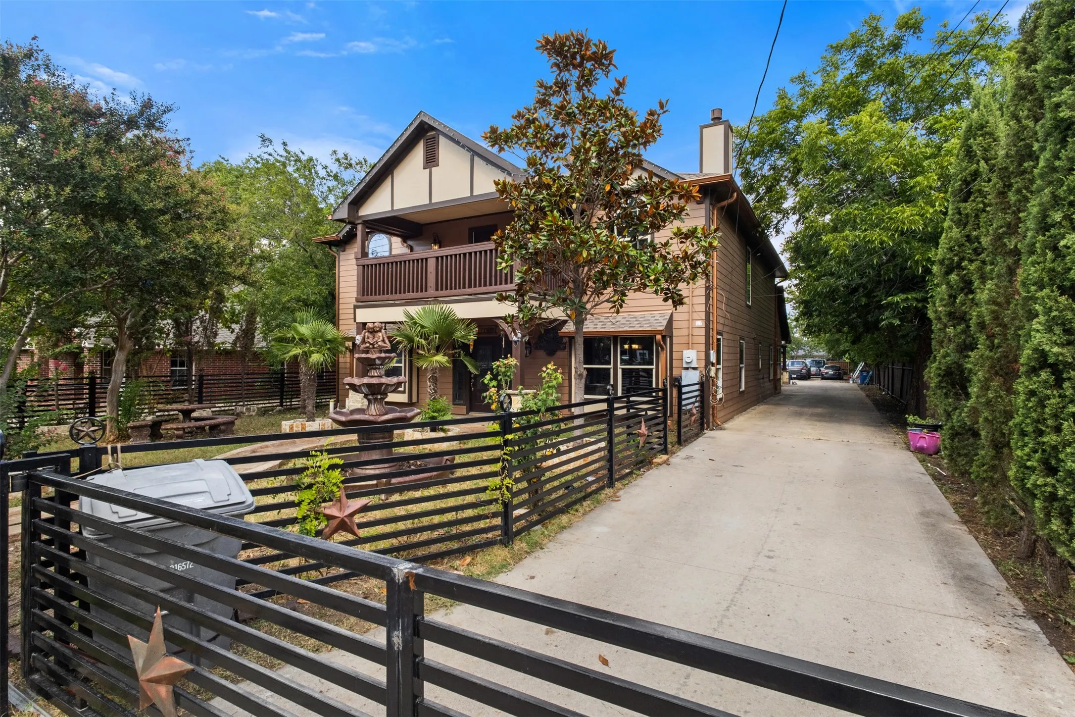 Two-story property featuring a stucco and siding exterior, upper-level balcony, and a multi-tiered water feature