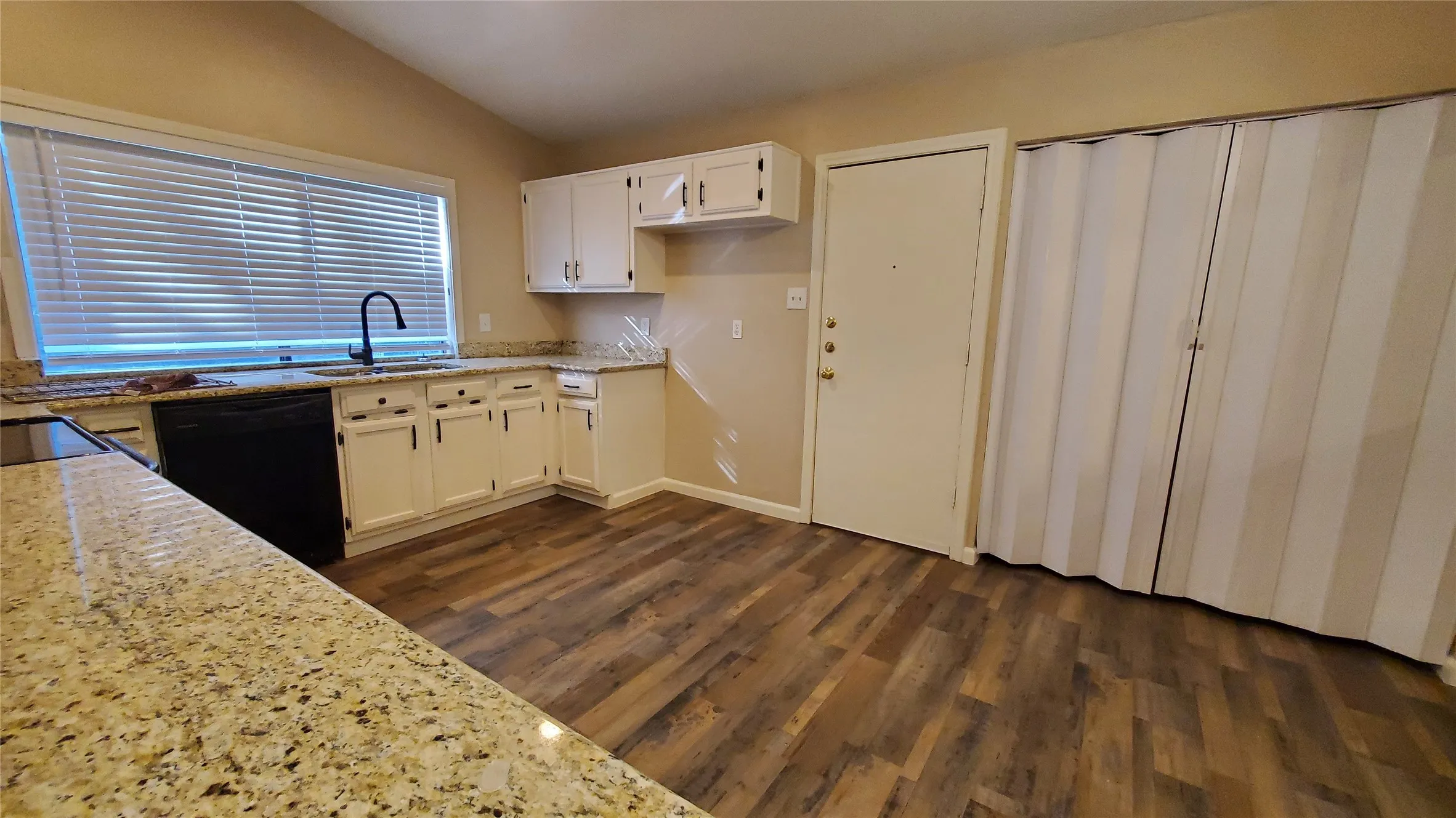 Kitchen with white cabinets, dark hardwood / wood-style flooring, lofted ceiling, and black appliances and smooth surface range.