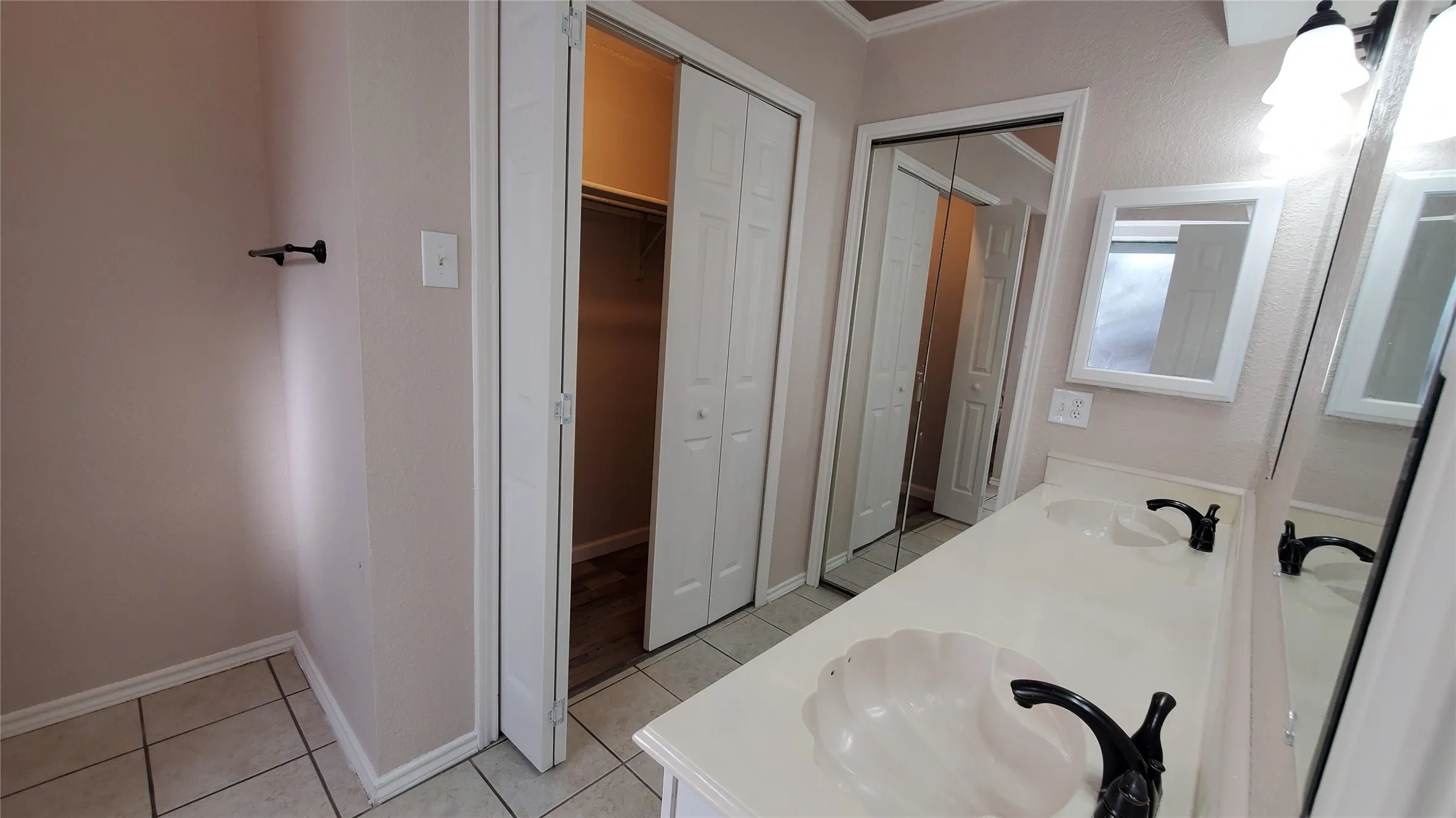 Bathroom with tile patterned flooring, vanity, dual closet space, and ornamental molding
