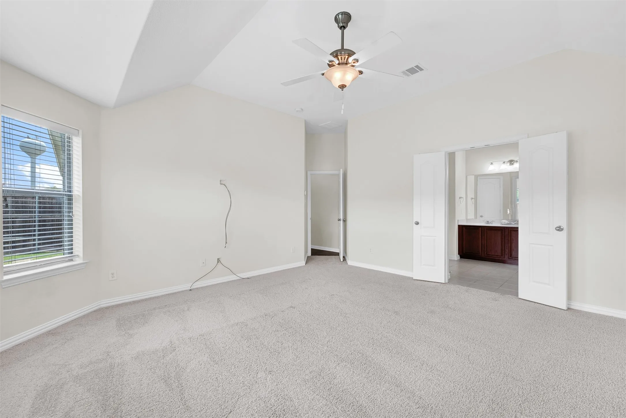 Room featuring vaulted ceiling, light-toned carpeting, and a ceiling fan with integrated lighting