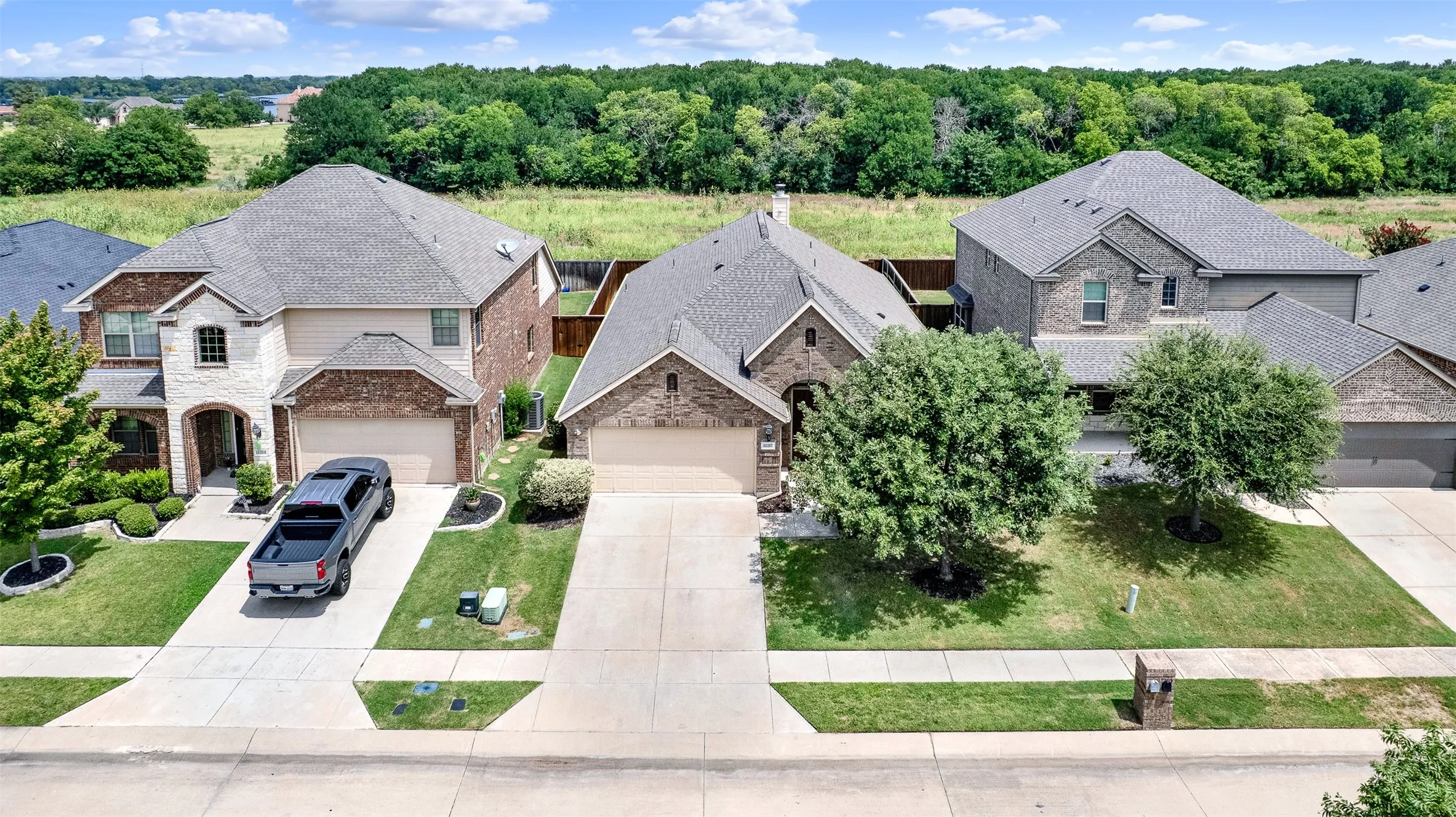 Two-story residence featuring a brick and stone facade, a two-car garage, and a manicured front lawn