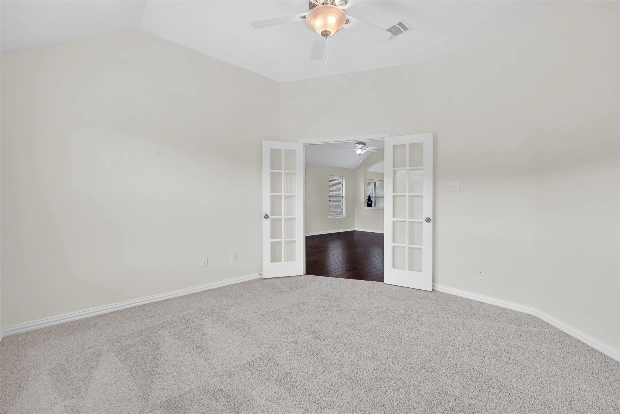 Carpeted room with vaulted ceiling and a ceiling fan with light fixture