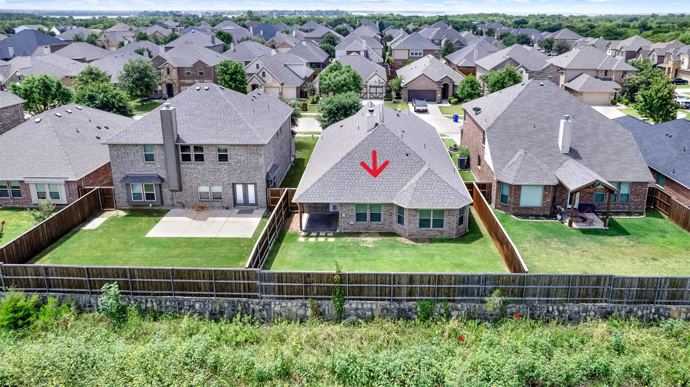 Rear exterior featuring a covered patio, fenced backyard, and a brick facade