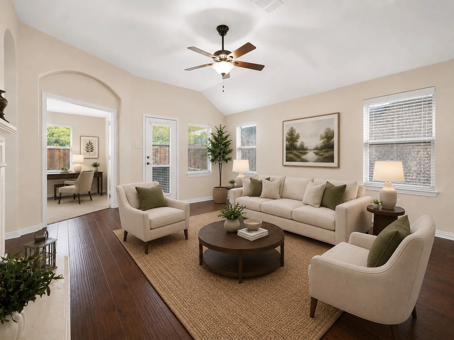 Spacious living area featuring vaulted ceilings, wood-finish flooring, and multiple windows