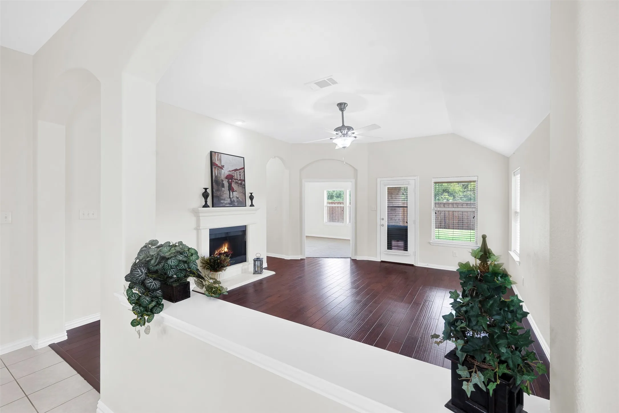 Spacious living area featuring rich wood-finish flooring and a white-mantled fireplace