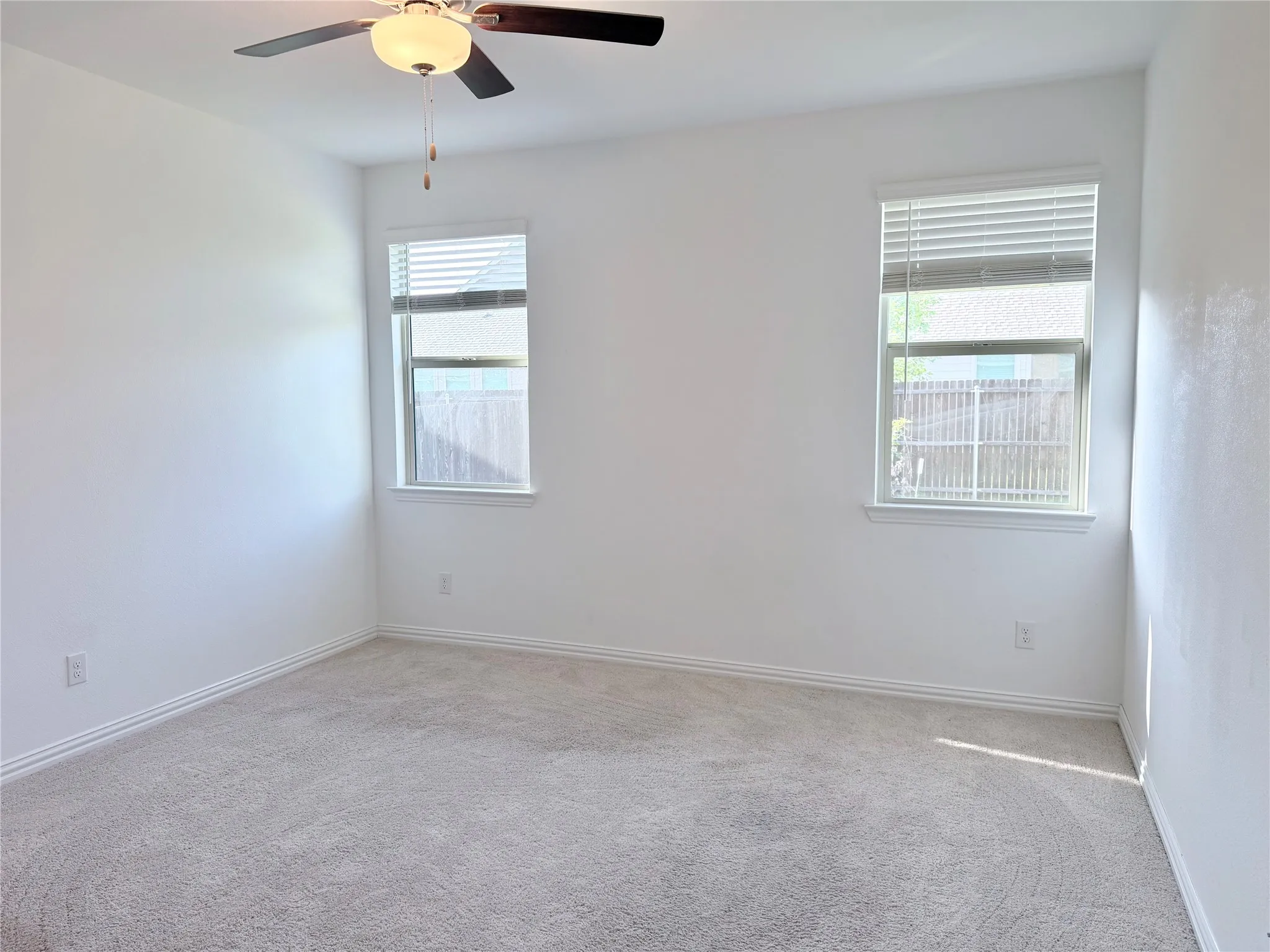 Spacious primary  bedroom featuring neutral carpeting, white walls, and a ceiling fan with integrated lighting