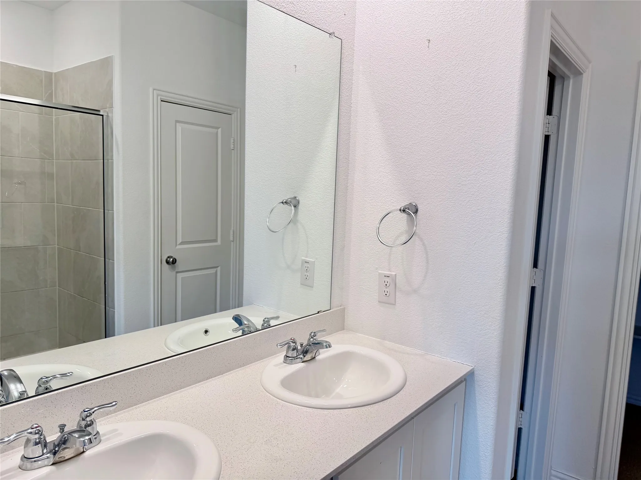 Double vanity with integrated sinks, chrome fixtures, and a large wall-mounted mirror