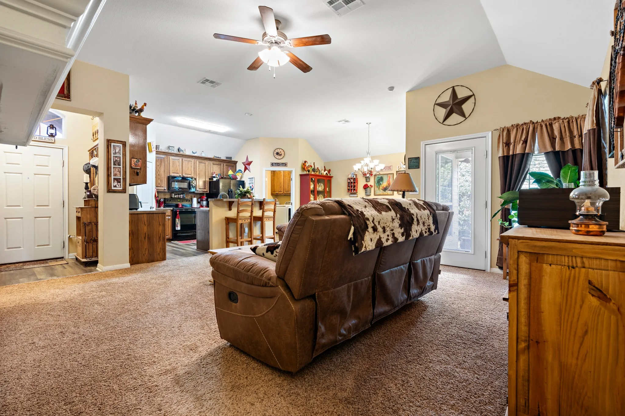 Spacious living area featuring vaulted ceilings, ceiling fan, and carpet flooring