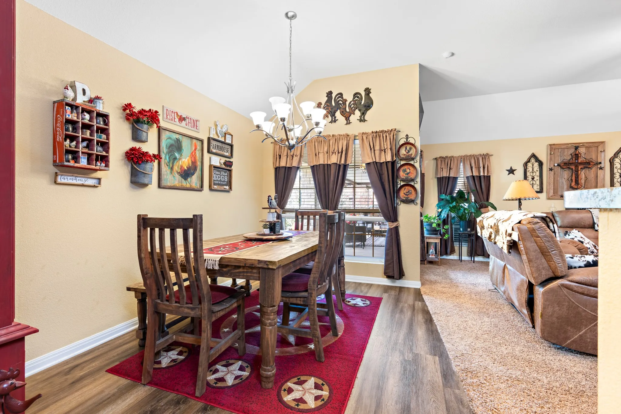 Open-concept dining area with wood-finish flooring, a contemporary chandelier, and a large window
