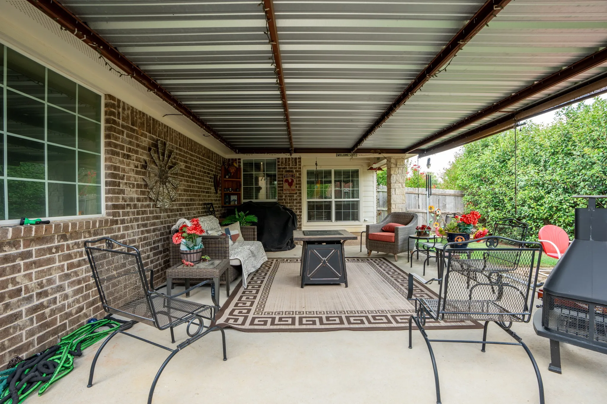 Covered patio featuring a solid roof structure, concrete flooring, and brick exterior walls