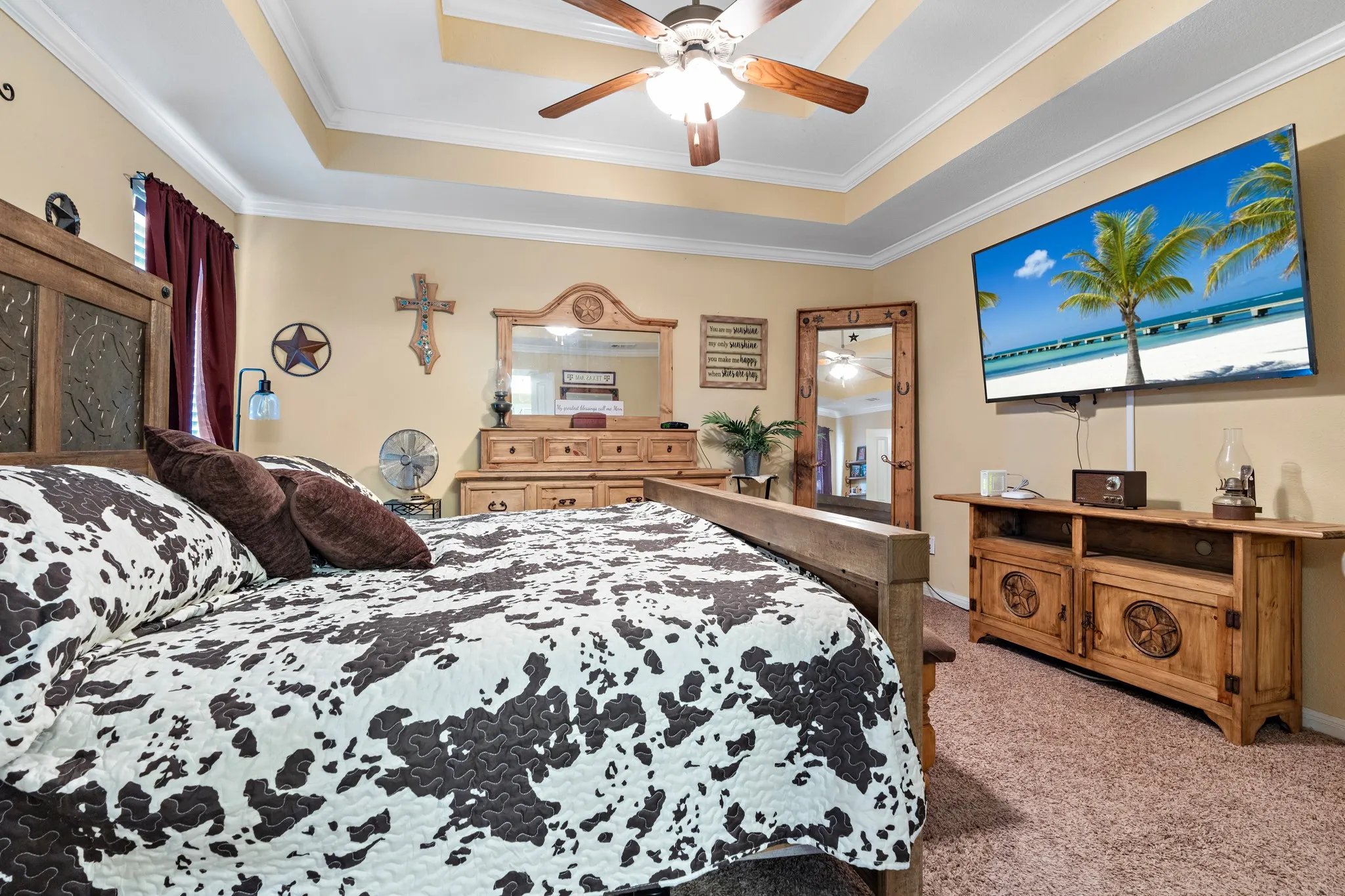 Bedroom with tray ceiling, crown molding, ceiling fan, carpet flooring, and a window with curtains