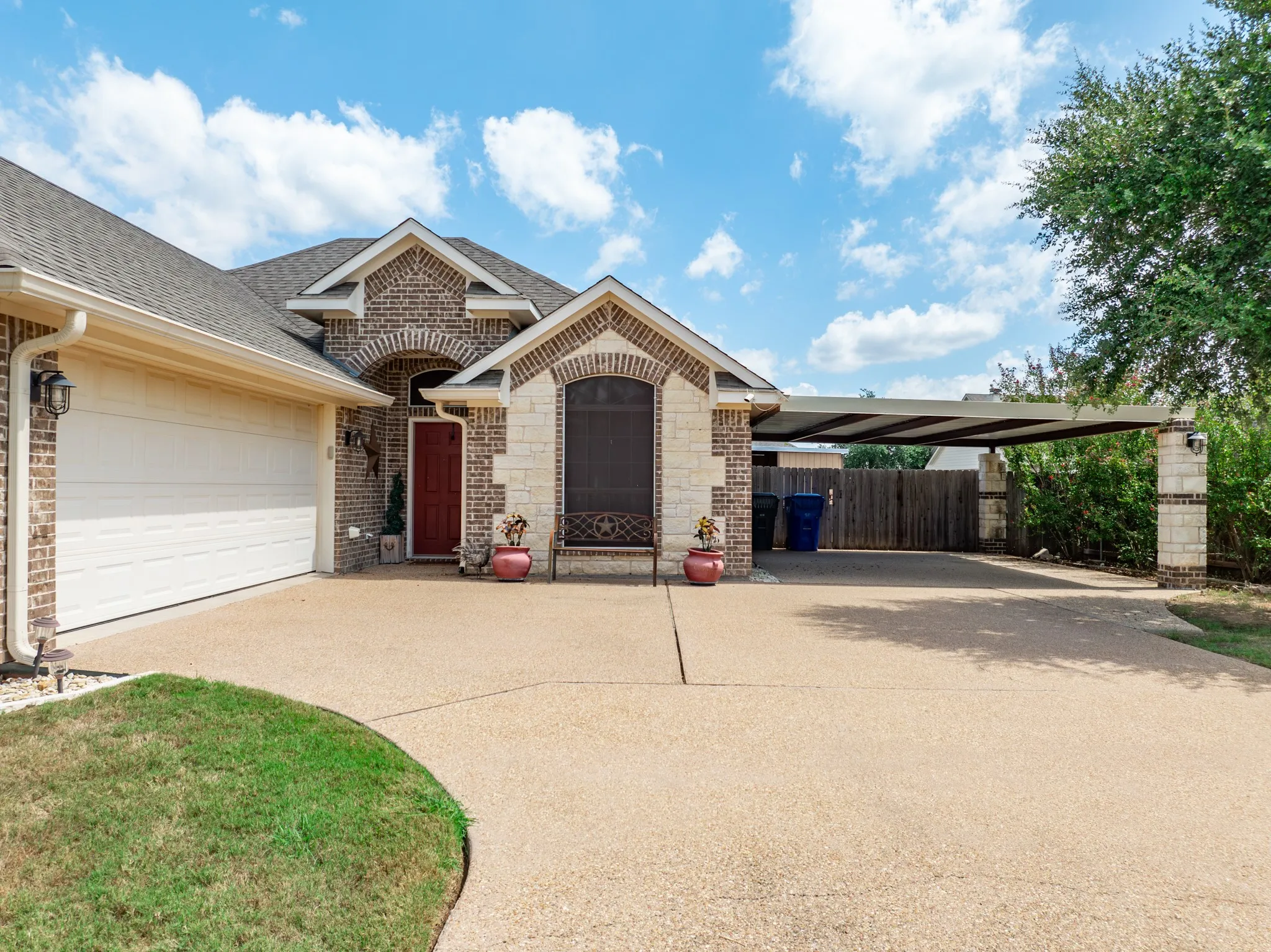 Exterior featuring a brick and stone facade, a two-car garage, and a covered carport