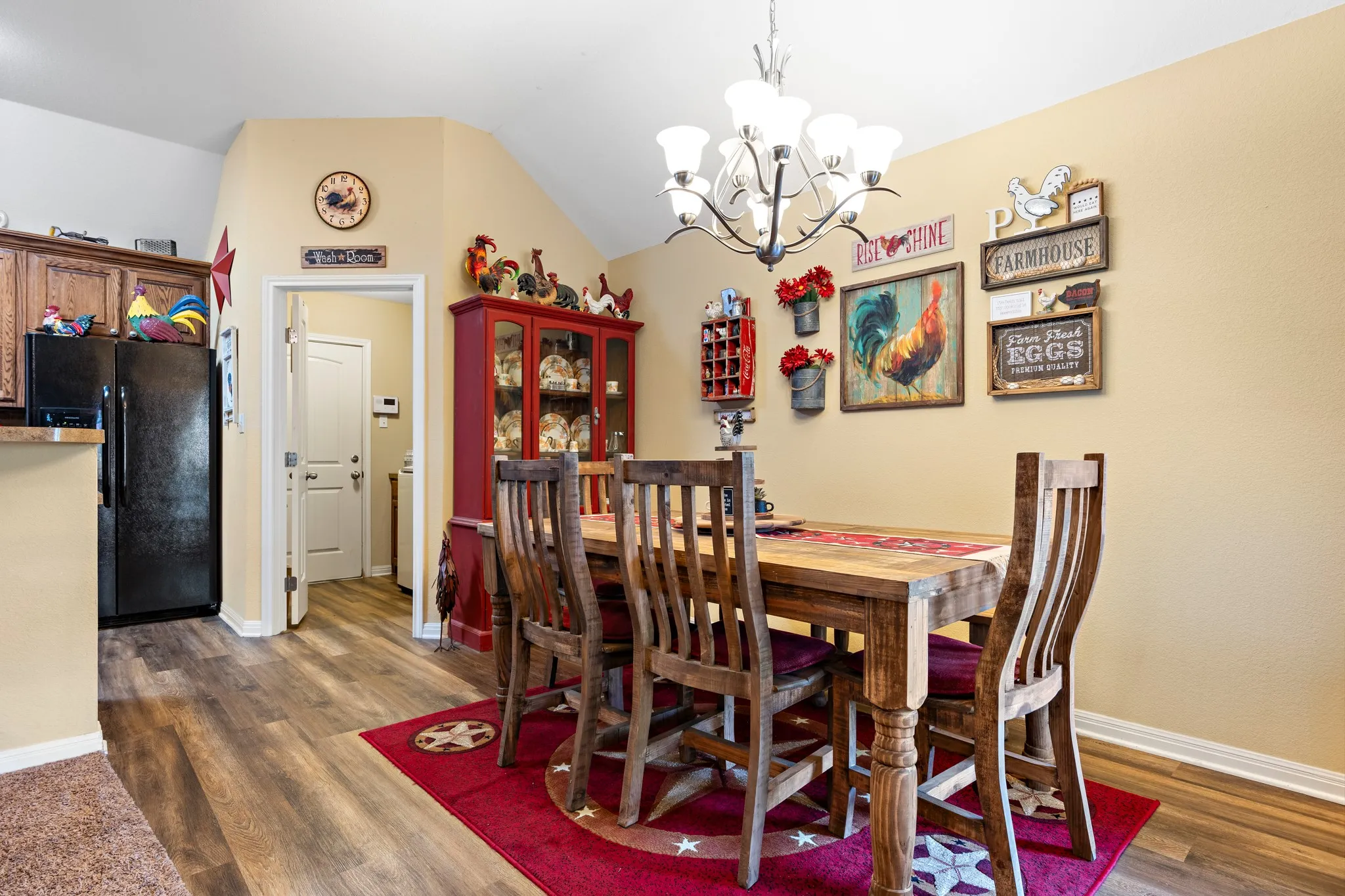 Dining area featuring vaulted ceilings, wood-finish flooring, a built-in display cabinet, and a chandelier with multiple light sources