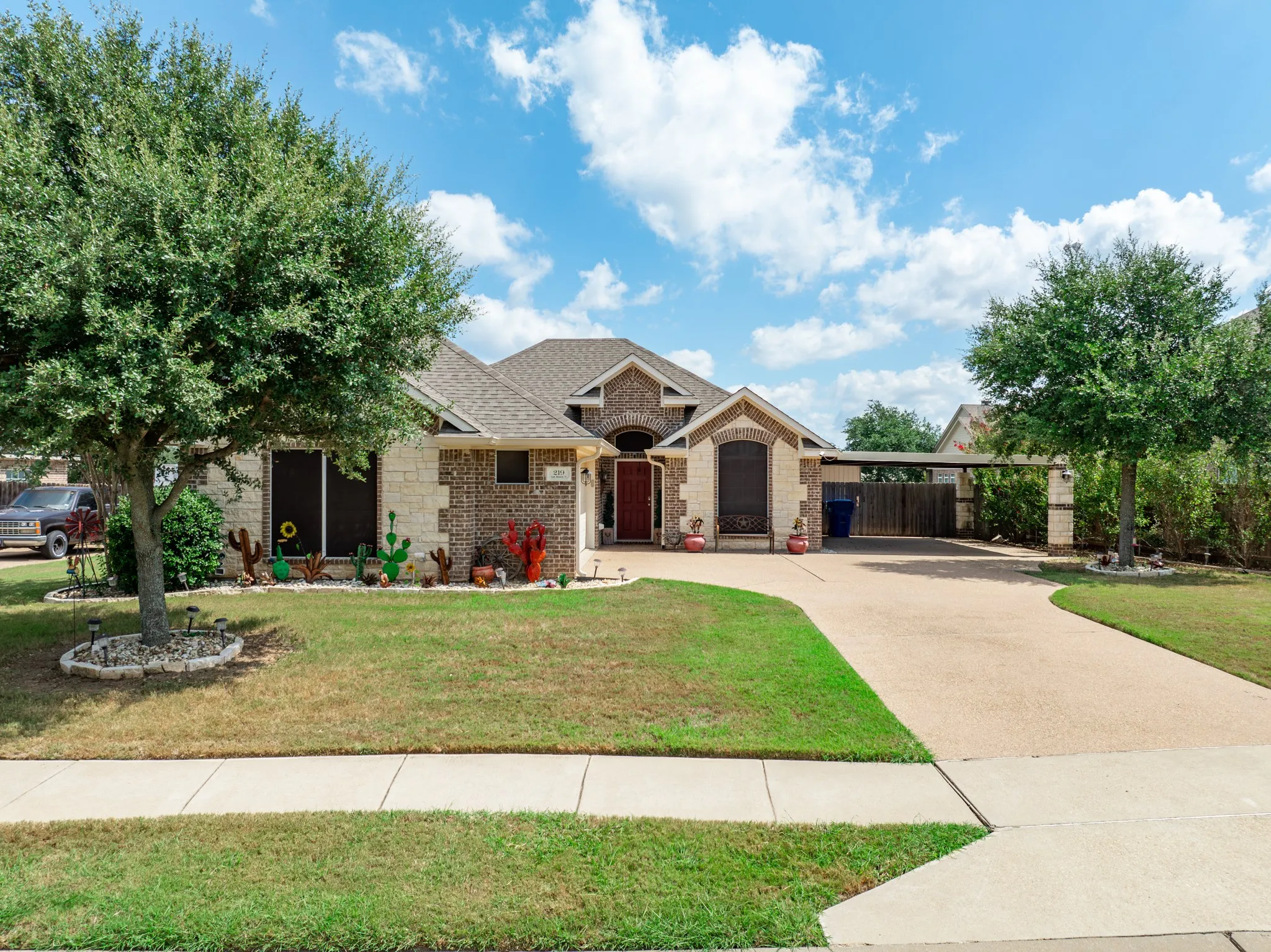 Brick and stone facade residence featuring a covered front entry, an attached carport, and a concrete driveway