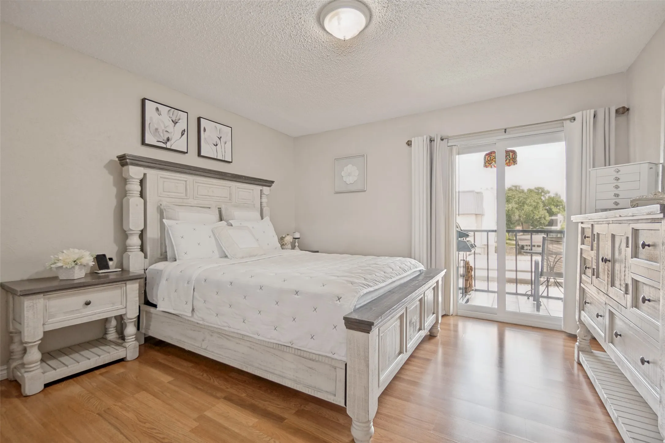 Bedroom featuring wood-finish flooring, a sliding glass door leading to an outdoor balcony, a flush-mount ceiling light fixture, and light-toned wall paint